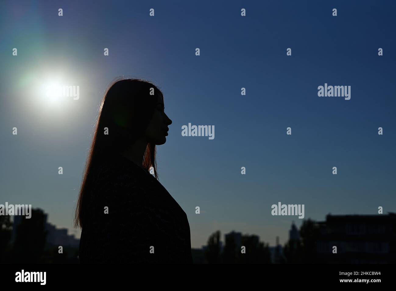 Silhouette Porträt der kaukasischen attraktive lange Haare Frau bei Sonnenuntergang, Bild gegen Sonne und blauen Himmel. Hochwertige Fotos Stockfoto