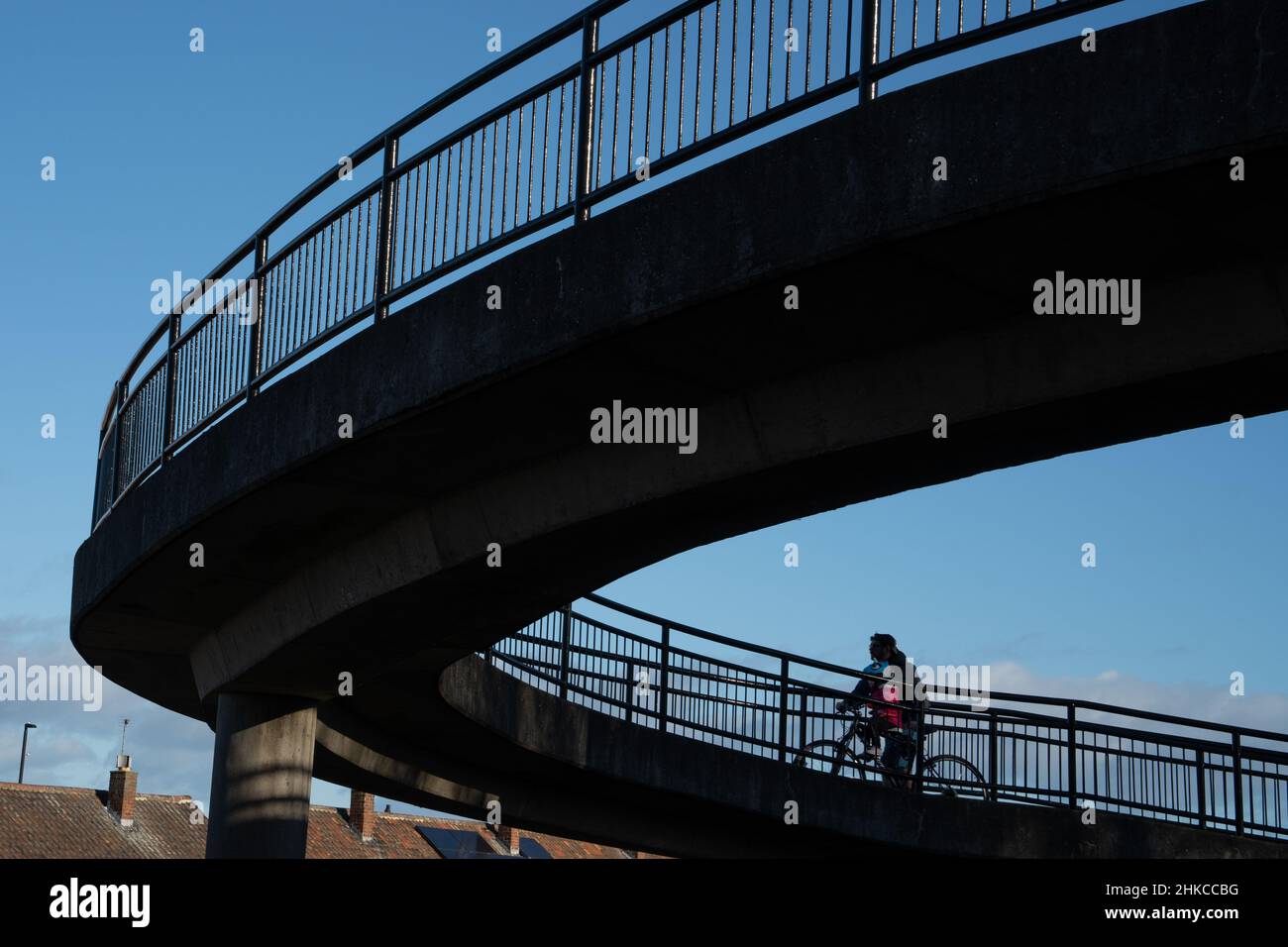 Ein Mann und ein Kind in Silhouette teilen sich ein Fahrrad, das eine Fahrradrampe am Bahnhof Longbenton, North Tyneside, Großbritannien, hinauffährt. Konzept des nachhaltigen Reisens. Stockfoto