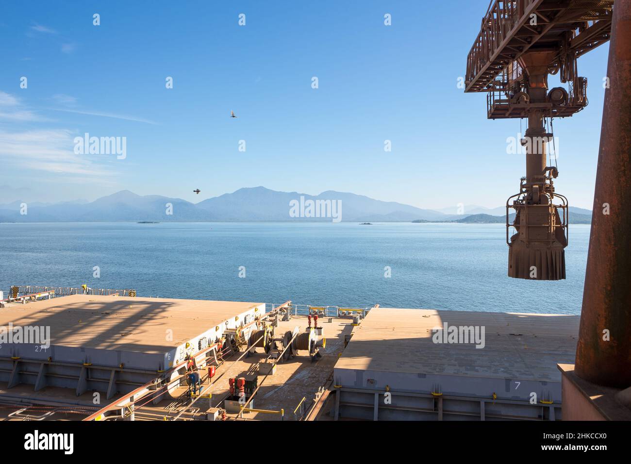 Bulk-Carrier-Frachtschiff mit Soja im Seehafen am sonnigen Sommertag geladen. Automatische Nahaufnahme des Laufbands. Konzept von Logistik, Handel, Wirtschaft. Stockfoto