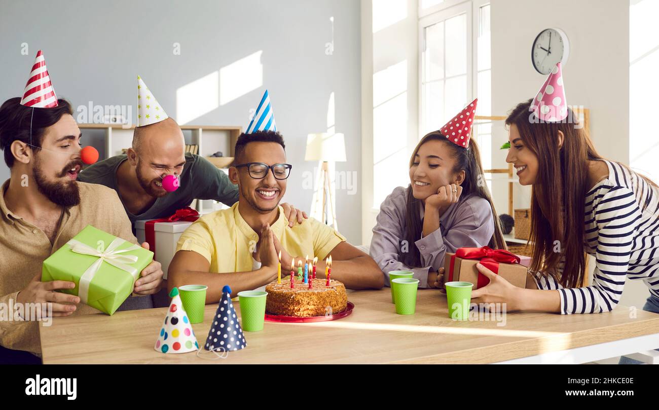 Glückliche Menschen begrüßen ethnischen männlichen Freund mit Geburtstag Stockfoto