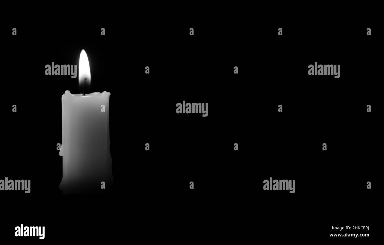 Kerze brennt auf dem schwarzen Hintergrund. Es gibt Platz für Ihren Text. Schwarzweiß-Foto. Das Konzept von Trauern, Trauer oder Trauer Stockfoto