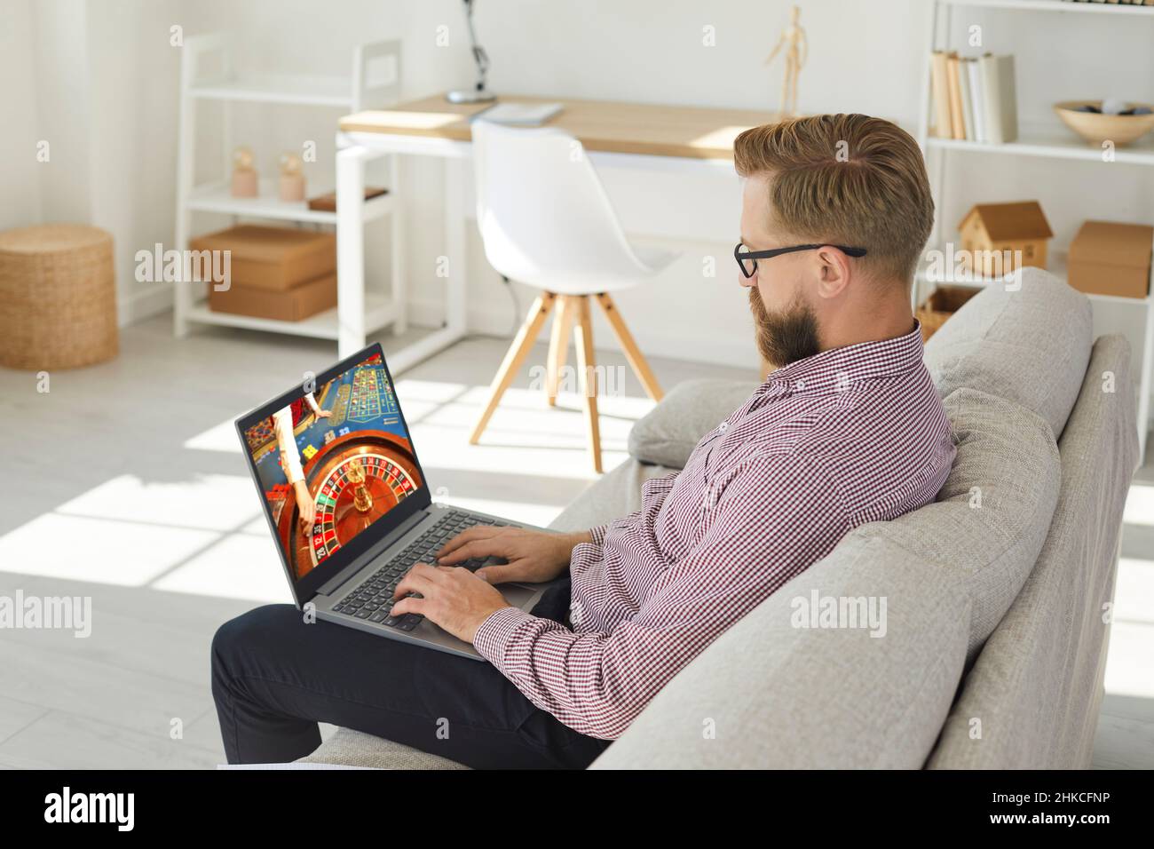 Mann entspannen auf dem Sofa spielen Online-Casino-Spiel Stockfoto