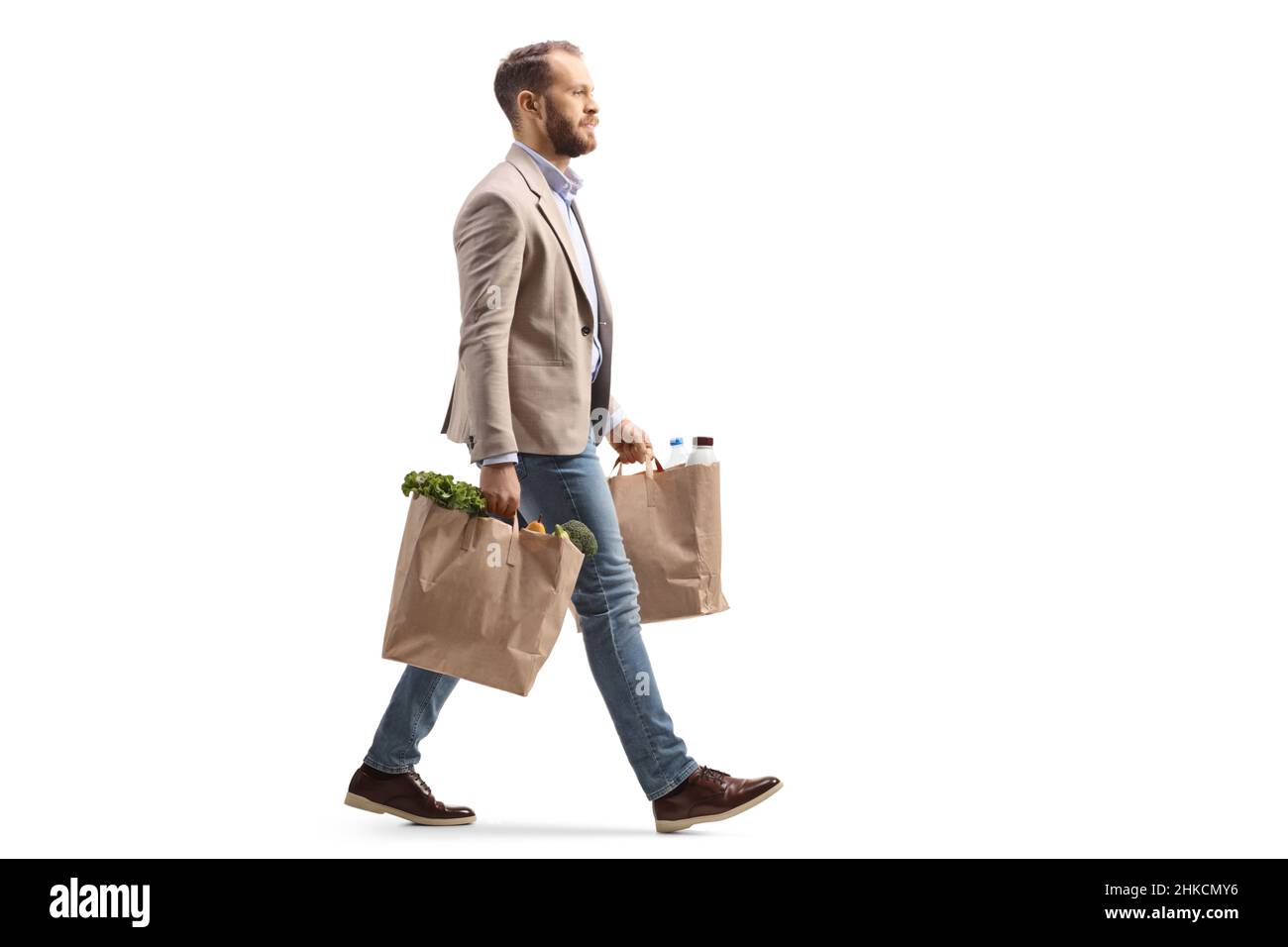 Mann, der auf weißem Hintergrund zwei Einkaufstüten trägt und läuft Stockfoto