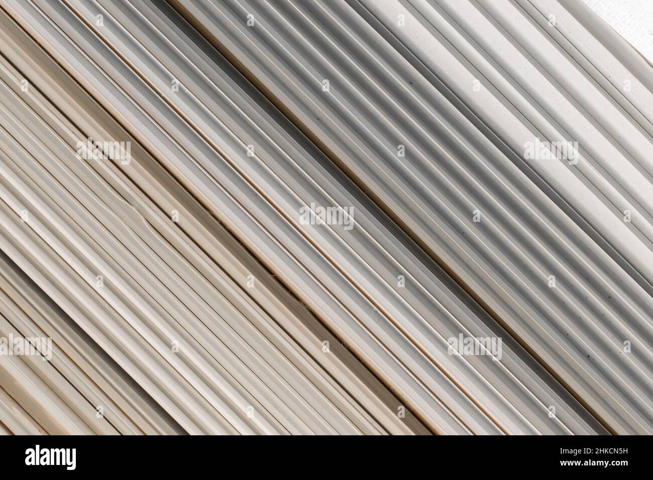 Alte PVC-Kunststoffpaneele in einem Stapel aus recyceltem Baumaterial. Textur Hintergrund mit Linien und Streifen Muster. Stockfoto