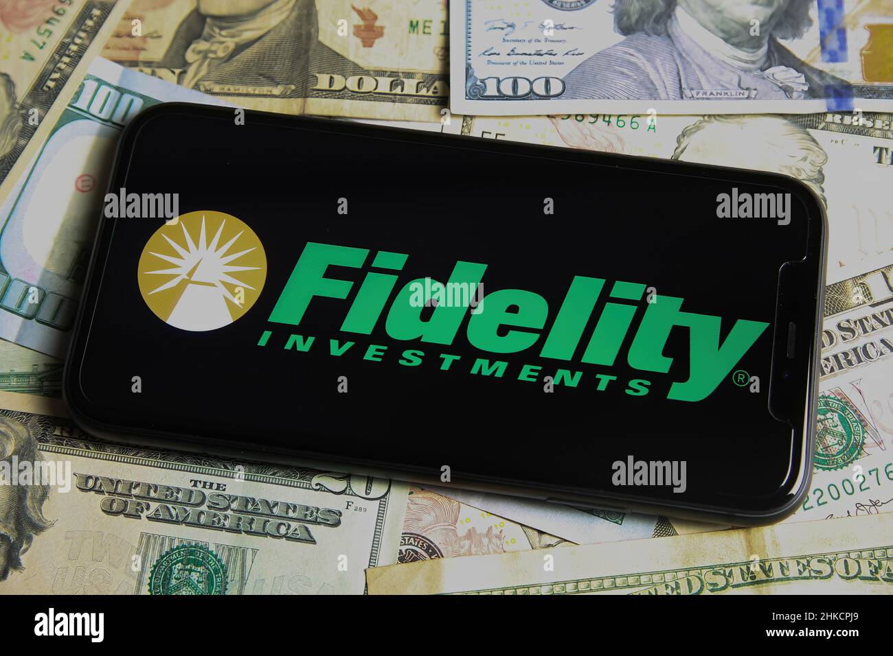 Viersen, Deutschland - Januar 9. 2022: Nahaufnahme des Mobiltelefons mit dem Logo von Treueanlagen, US-Dollar-Papierbanknoten im Hintergrund Stockfoto