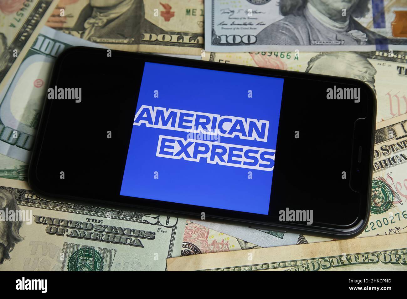 Viersen, Deutschland - Januar 9. 2022: Nahaufnahme des Mobiltelefons mit dem Logo des american Express, US-Dollar-Papierbanknoten im Hintergrund Stockfoto