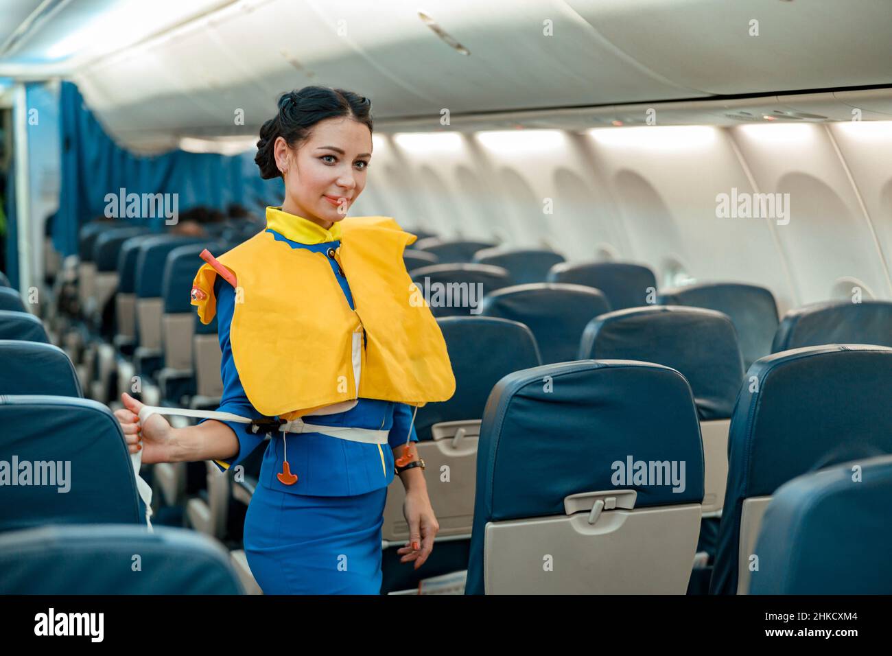 Stewardess demonstriert, wie man Rettungsweste im Flugzeug verwendet Stockfoto