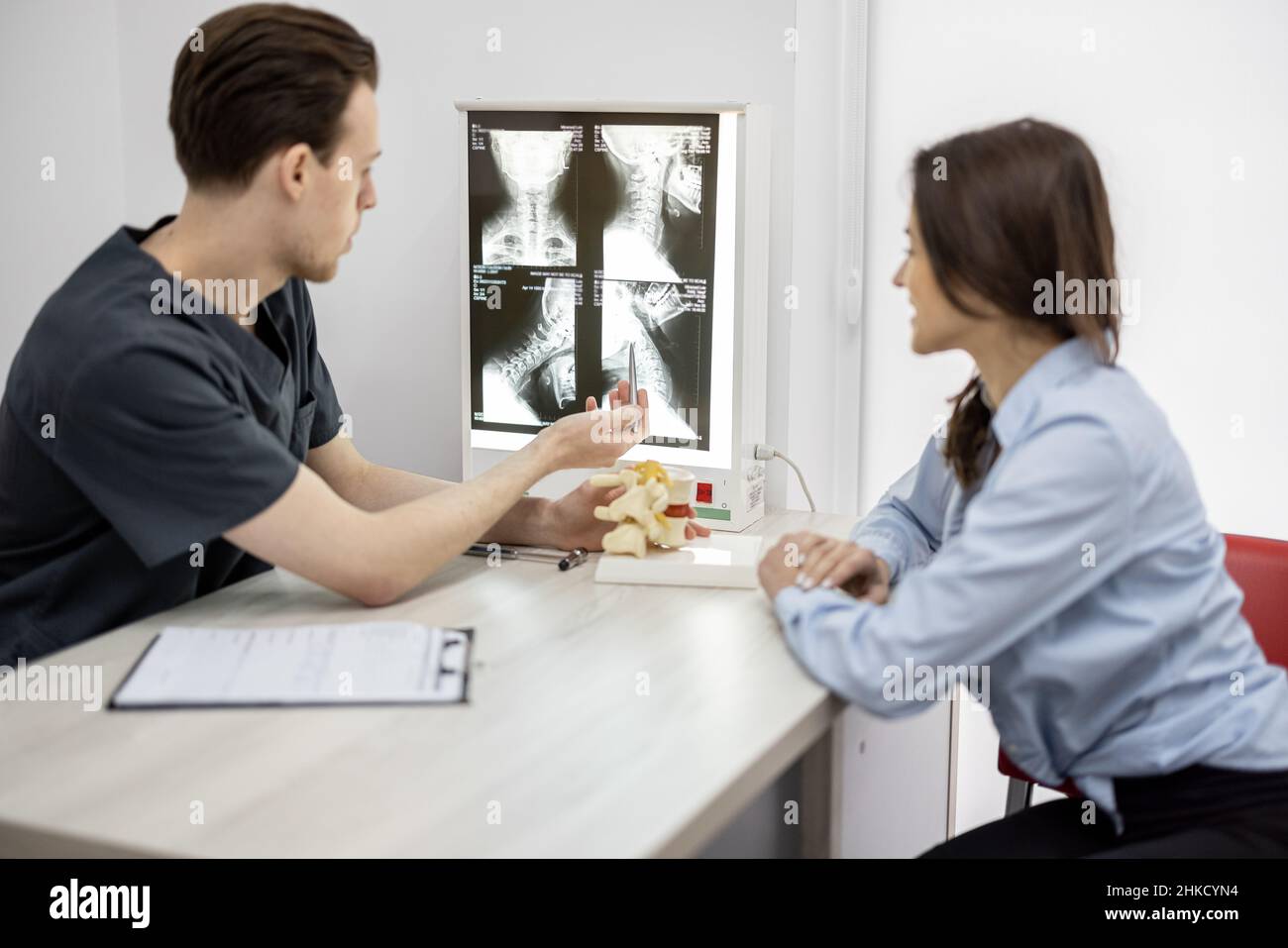 Junge Frau in Absprache mit einem Physiotherapeuten in der Arztpraxis Stockfoto