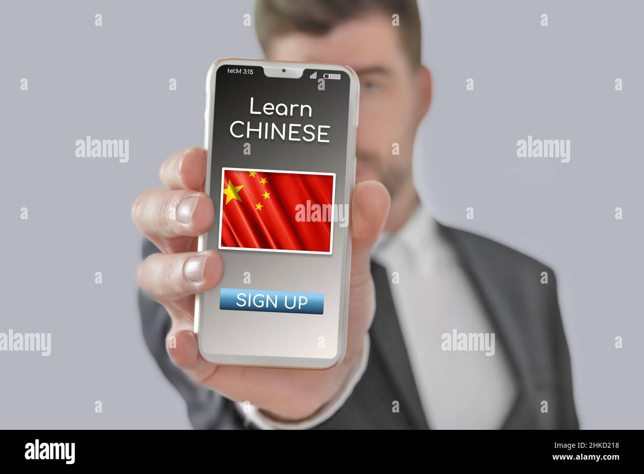 Online-Konzept Lernen Sie die chinesische Sprache mit einer Person, die E-Learning-App auf dem Mobiltelefon zeigt, wobei die Flagge Chinas isoliert ist Stockfoto