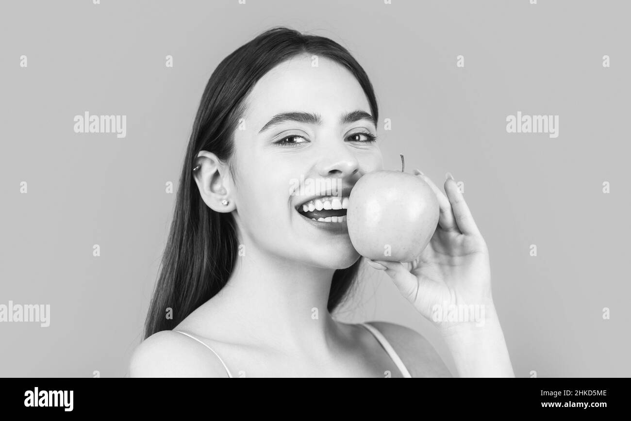 Stomatologie-Konzept. Frau mit perfektem Lächeln hält Apfel, blauer Hintergrund. Frau essen grünen Apfel. Porträt von jungen schönen glücklich lächelnden Frau Stockfoto