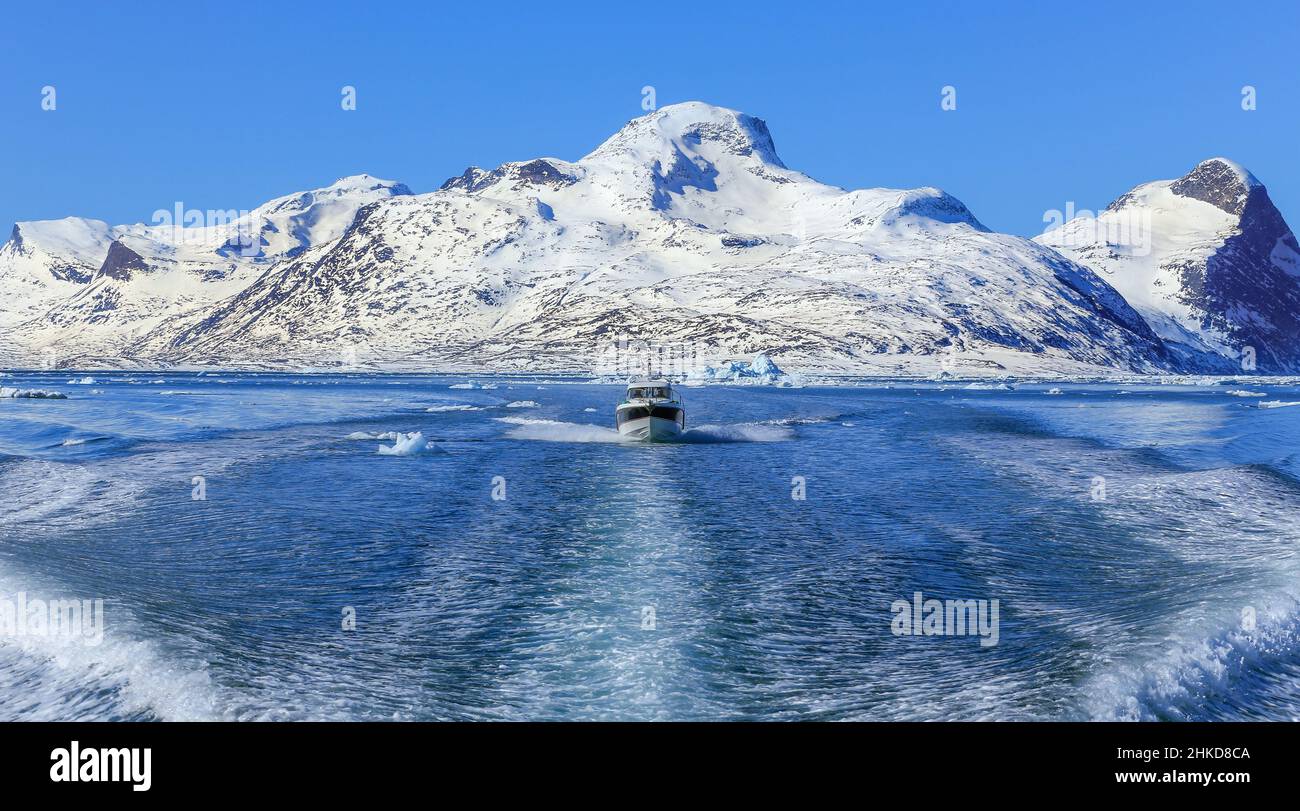 Motorboot in der Mitte des Nuuk Fjords mit gefrorenen Felsen im Hintergrund, Grönland Stockfoto