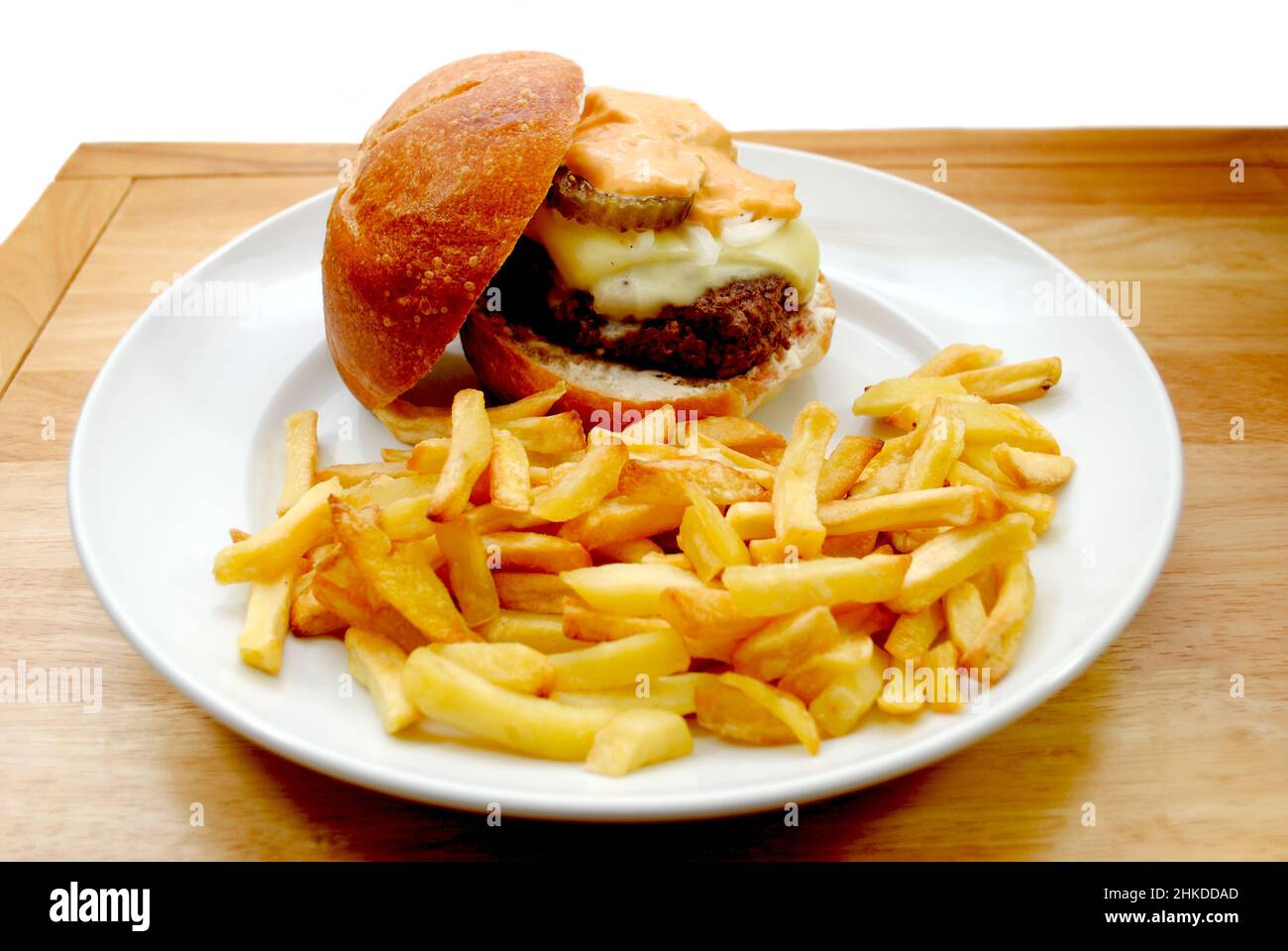 Knusprige Pommes in einem Teller mit einem Cheeseburger im Hintergrund Stockfoto