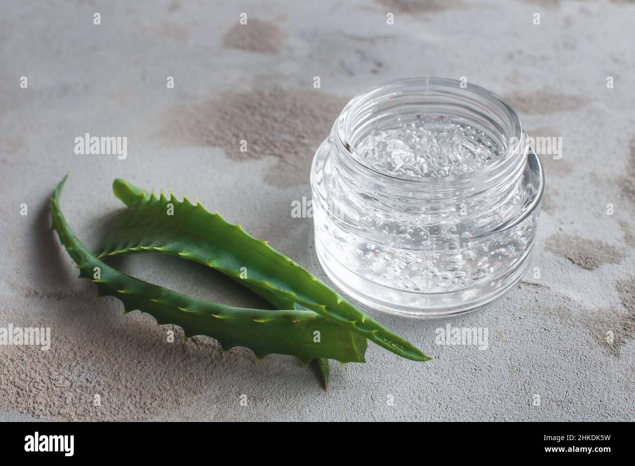 Geltextur mit Blasen Hyaluronsäure und Aloe Vera verzweigt sich in einem Glasgefäß auf einem betonierten Hintergrund Stockfoto