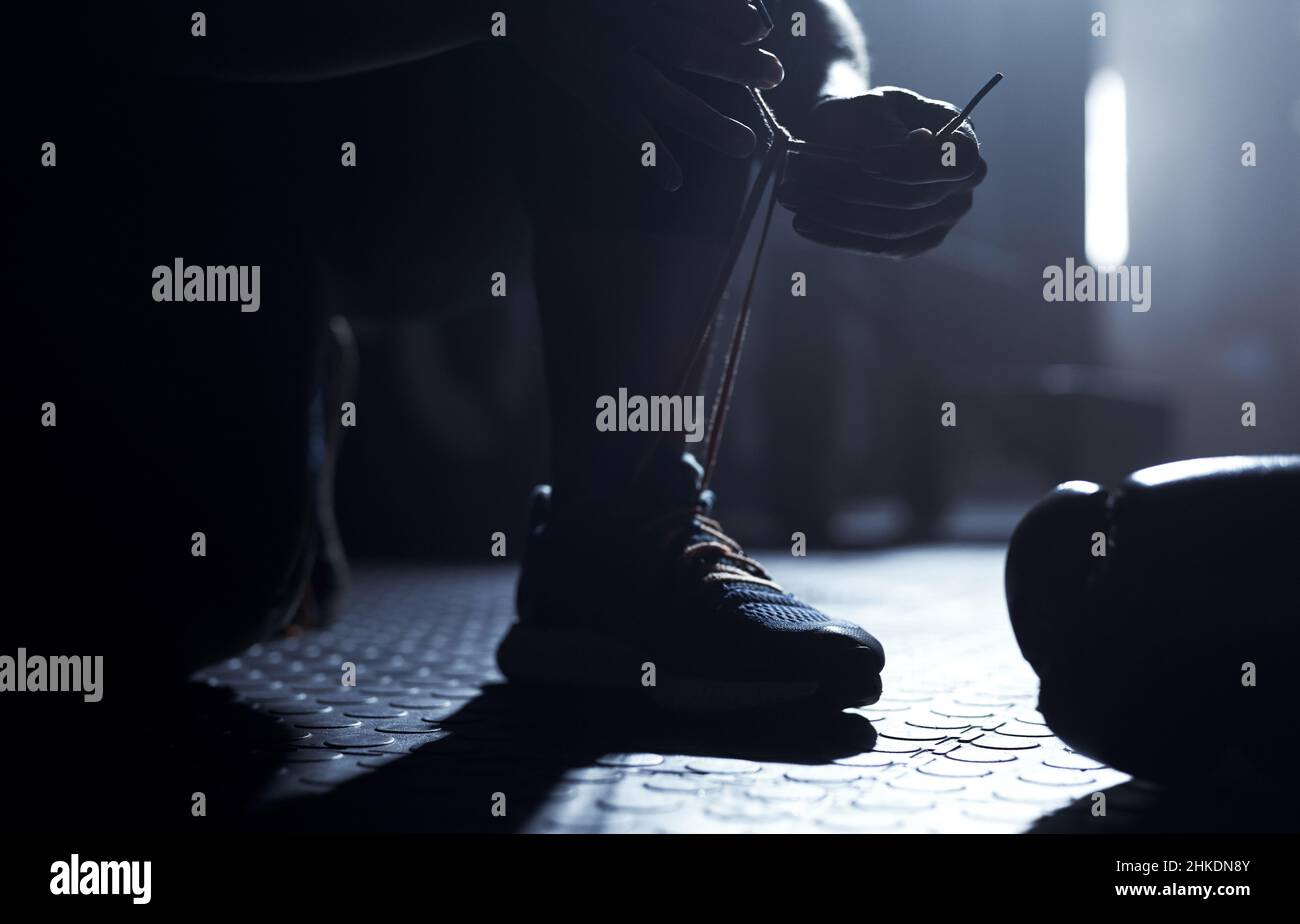 Noch mehr Spielspaß. Nahaufnahme eines nicht erkennbaren Mannes, der seine Schnürsenkel in einem Fitnessstudio bindet. Stockfoto