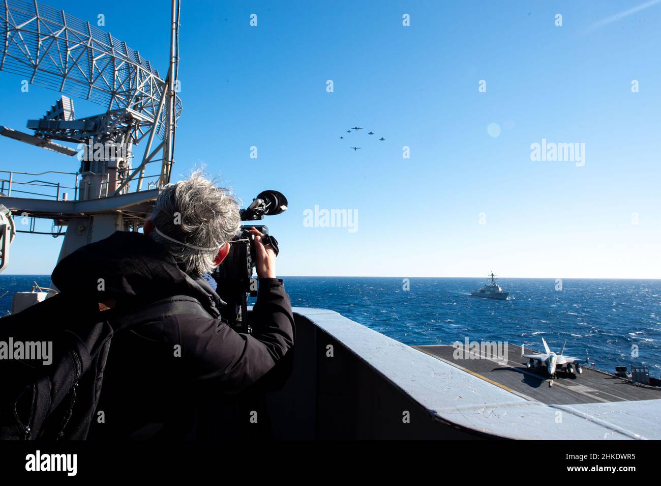 220202-N-EJ940-1057 ADRIA (FEB 2, 2022) Ein Videofilmer der Nachrichtenmedien nimmt Flugzeuge auf, die Carrier Air Wing (CVW) 1 und der italienischen Marine zugewiesen wurden, während sie über die Adria fliegen, als der Arleigh Burke-Klasse Lenkraketen-Zerstörer USS Bainbridge (DDG 96) und der Nimitz-Klasse Flugzeugträger USS Harry S. Truman (CVN 75) Transit the Adriatic Sea zur Unterstützung von Neptune Strike 22, 2. Februar 2022. Neptune Strike 22 unterstreicht die natürliche Entwicklung der Fähigkeit der NATO, die High-End-Fähigkeiten der maritimen Kriegsführung einer Trägerstreikgruppe zu integrieren, um die Verteidigung der Allianz zu unterstützen. (USA Marineblau Stockfoto