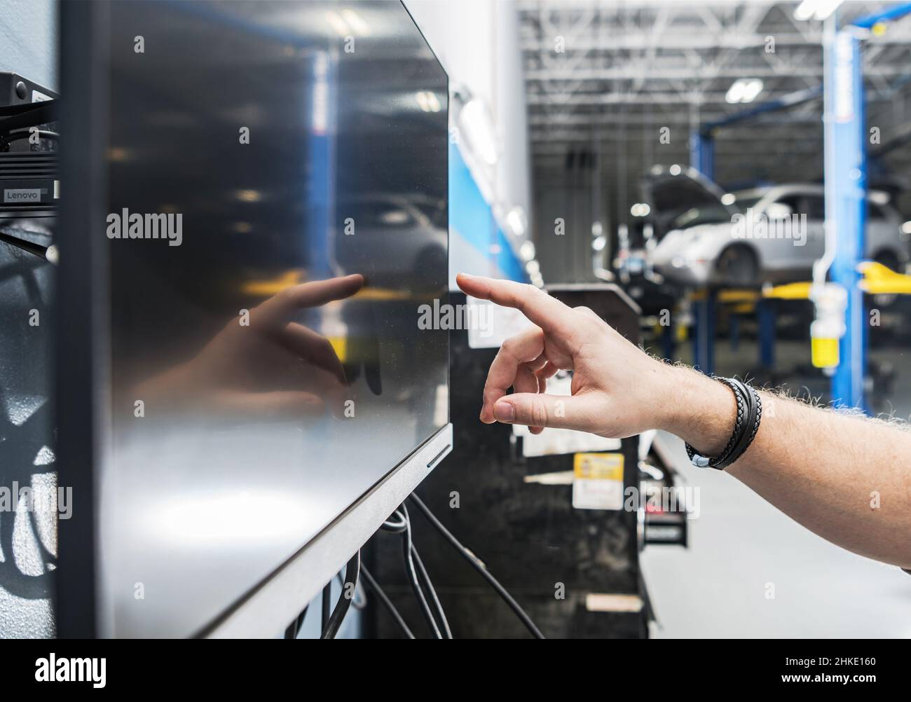 Auto-Service-Techniker, der auf seinem Computer im Fahrzeugservice nach Autoteilen sucht. Automobilcomputer. Stockfoto