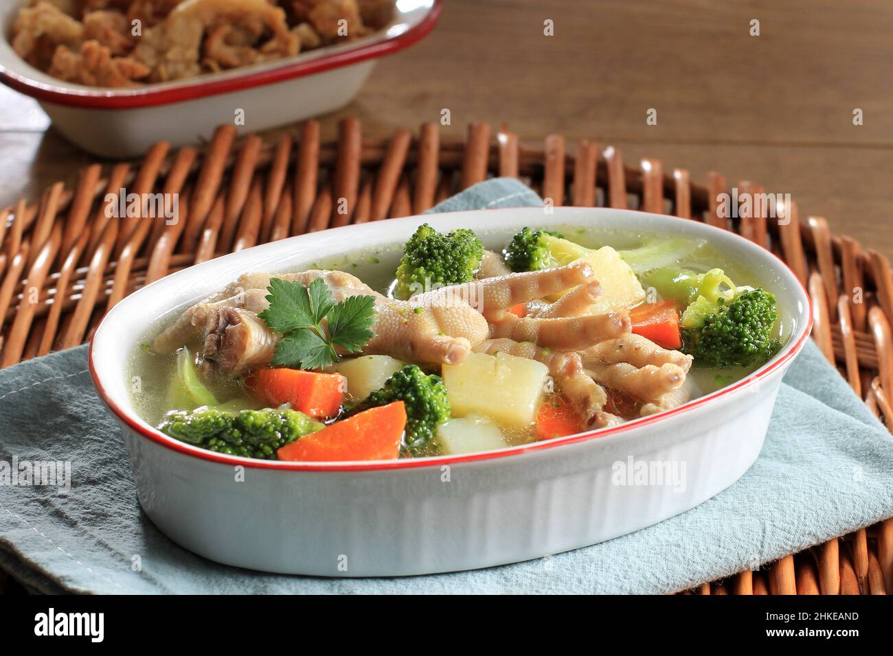 Hähnchenfüße, klare Suppe, leichte Brühe mit Brokkoli, Karotten und Kartoffel auf Keramikschüssel. Beliebt als SOP Ceker in Indonesien Stockfoto