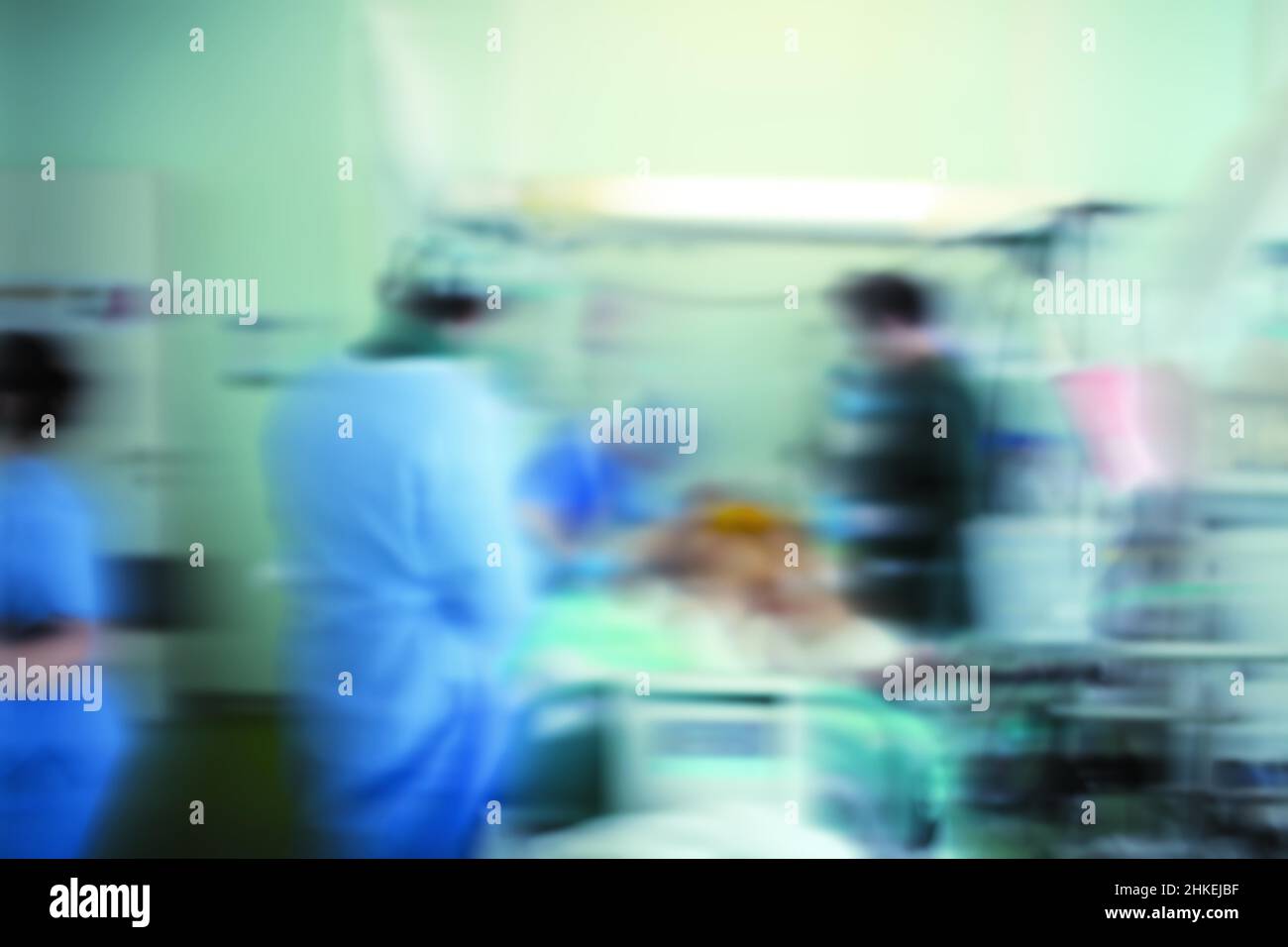 Unfokussierter Hintergrund mit einem medizinischen Team, das mit einem bewusstlosen Patienten auf der Intensivstation arbeitet. Stockfoto