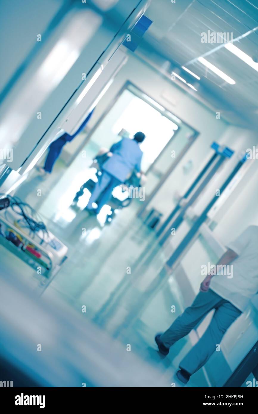 Krankenhausflur während der täglichen Routnearbeit mit vorbeifahrenden Mitarbeitern, medizinischer Hintergrund. Stockfoto