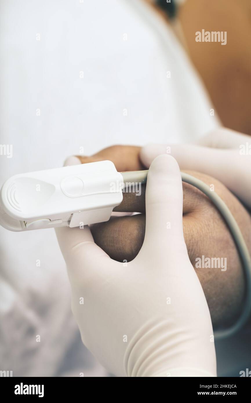 Die Krankenschwester hält die Hand des Patienten mit einem angebrachten Pulsoximeter als Symbol für Barmherzigkeit und Mitgefühl. Stockfoto