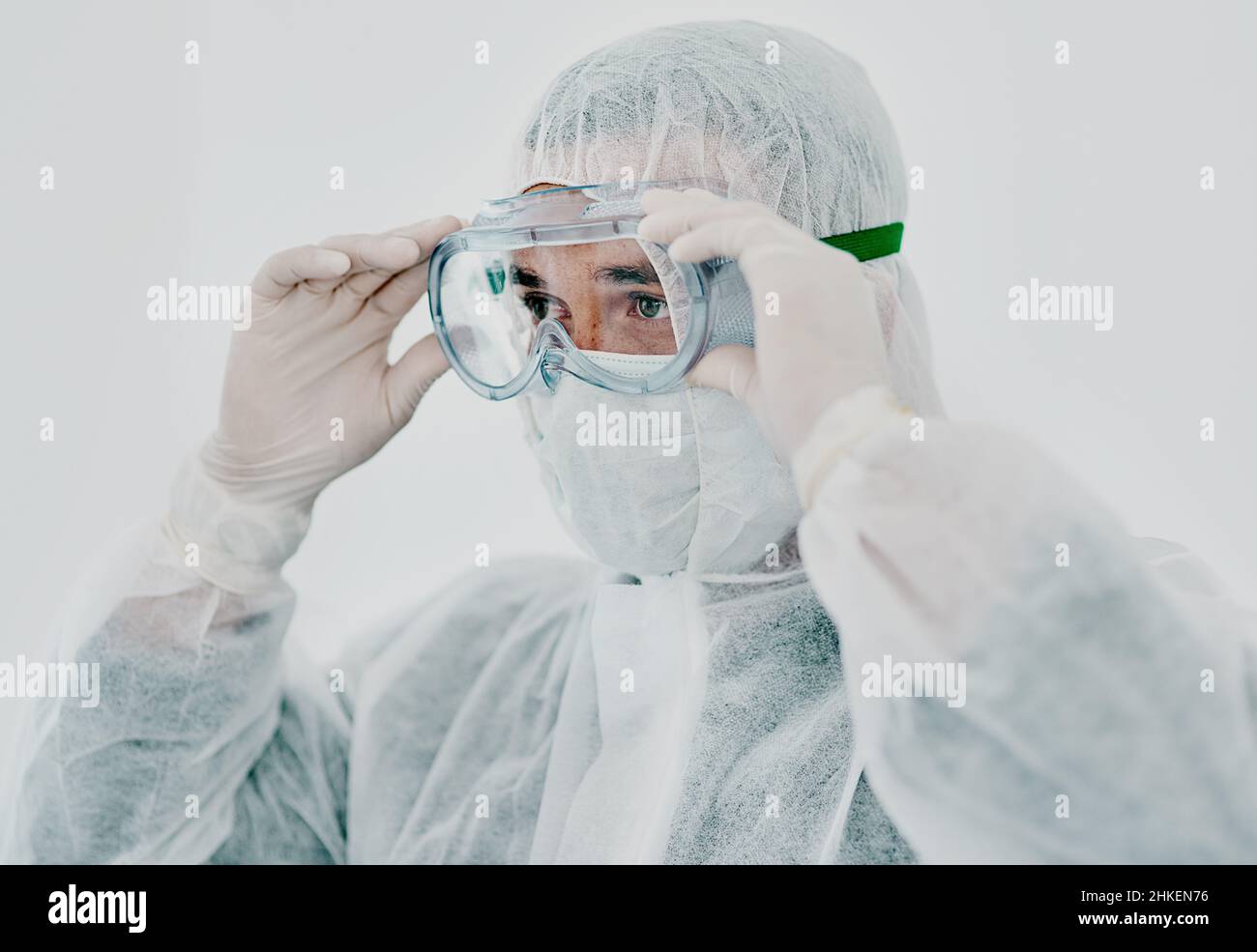 Zeit, die Dinge unter Kontrolle zu bekommen. Aufnahme eines jungen Mannes, der vor der Dekontamination seine Schutzkleidung auflegte. Stockfoto