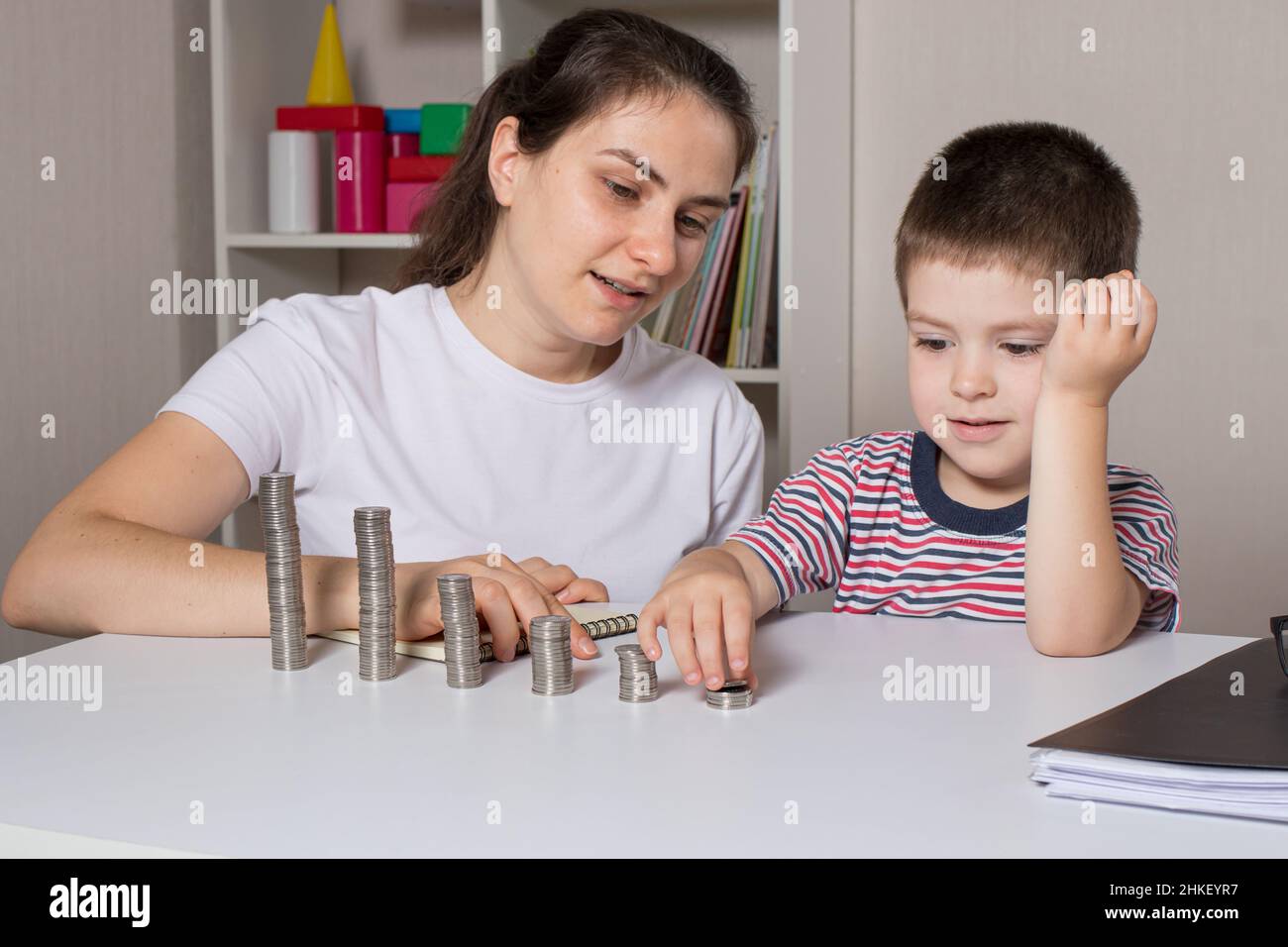 Mutter und Kind lernen finanzielle Bildung für Kinder, um zu investieren. Geld, Münzen, Einkommenswachstum und Kauf von Aktien. Stockfoto