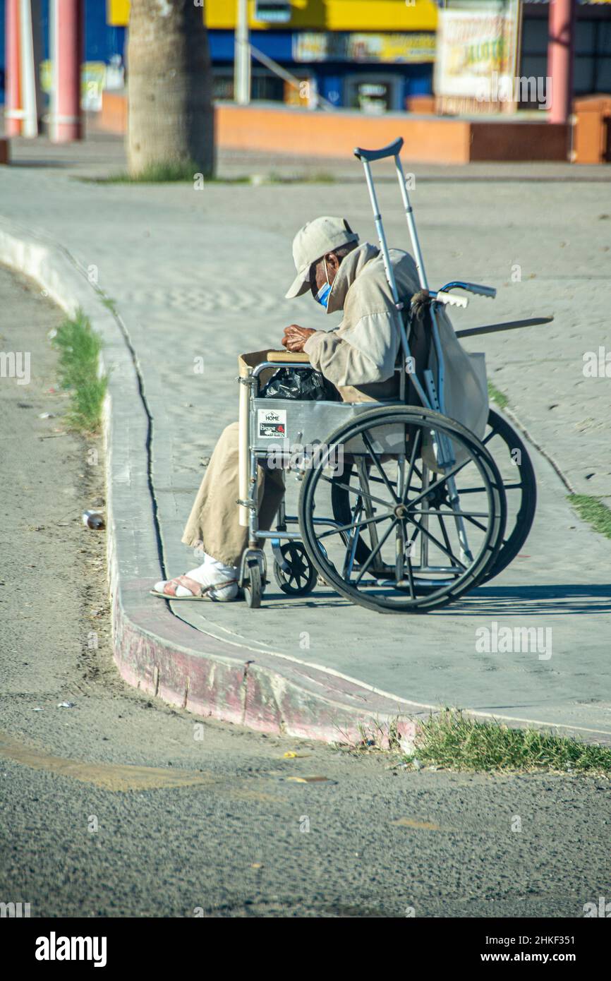 Ein Mexikaner im Rollstuhl verbringt seine Tage damit, Müll entlang der Rinnen der Straßen von Puerto Penasco, Sonora, Baja California, Mexiko, abzuholen. Stockfoto