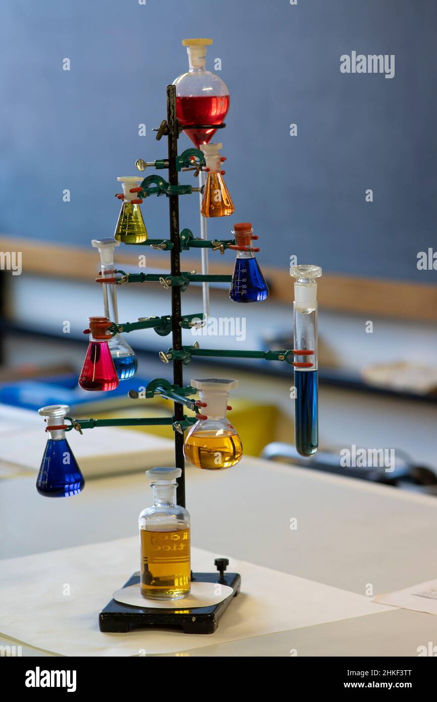Chemielabor der Schule. Verschiedene farbige Lösungen in Kolben mit Tafel im Hintergrund. Stockfoto