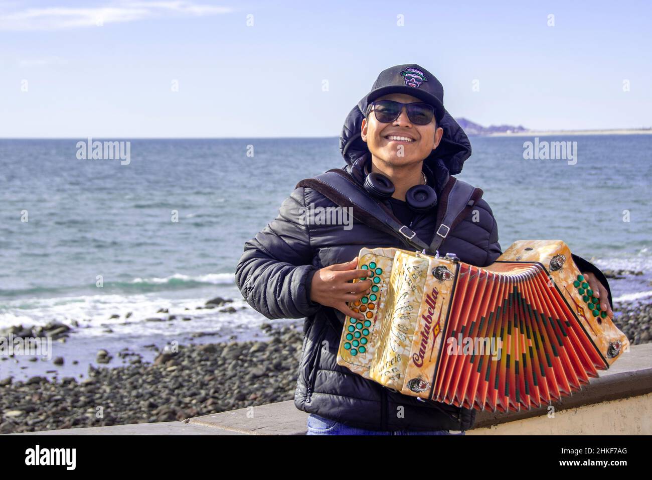 Ein junger Mann Mitte zwanzig, der mit seiner Ziehharmonika auf dem Malecon posiert; Puerto Penasco, Baja California, Mexiko. Stockfoto