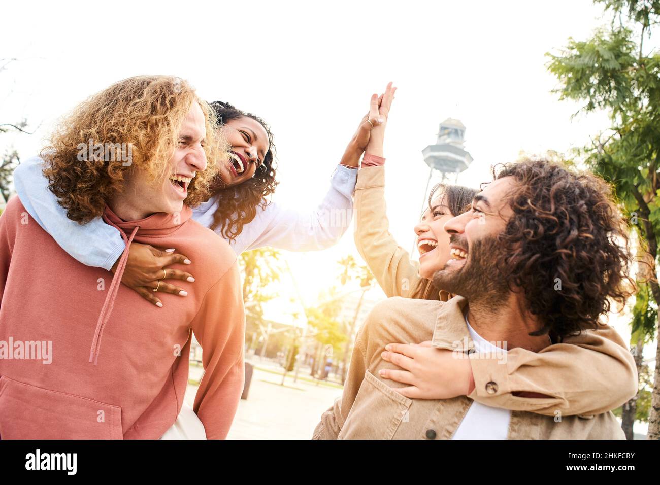 Glückliche Menschen Huckepack. Gruppe von lächelnden Freunden feiern geben High Five feiern Erfolg und Spaß zusammen in einem Park der Stadt. Stockfoto