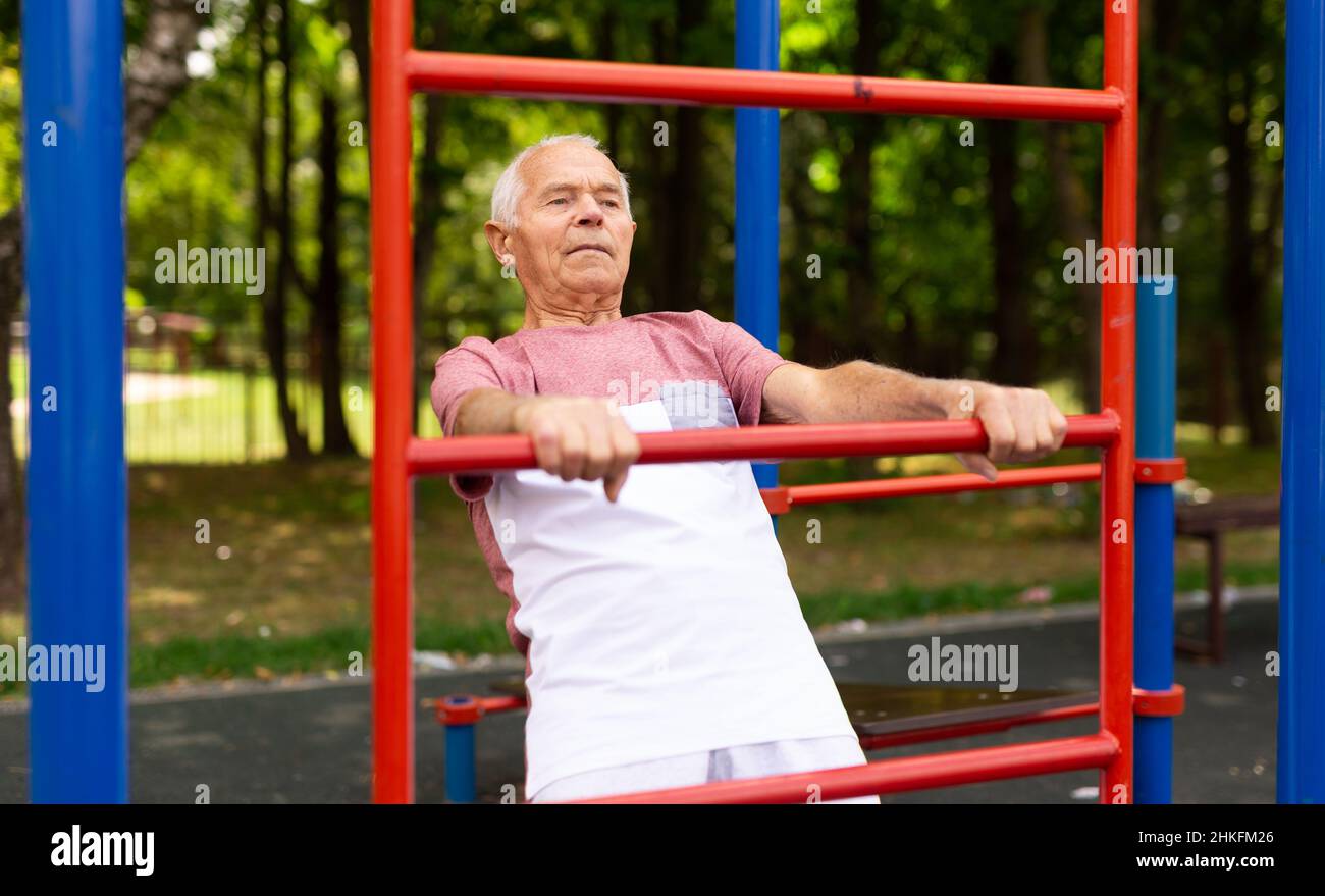Alter Mann macht Übungen auf einer vertikalen Leiter im Freien Stockfoto