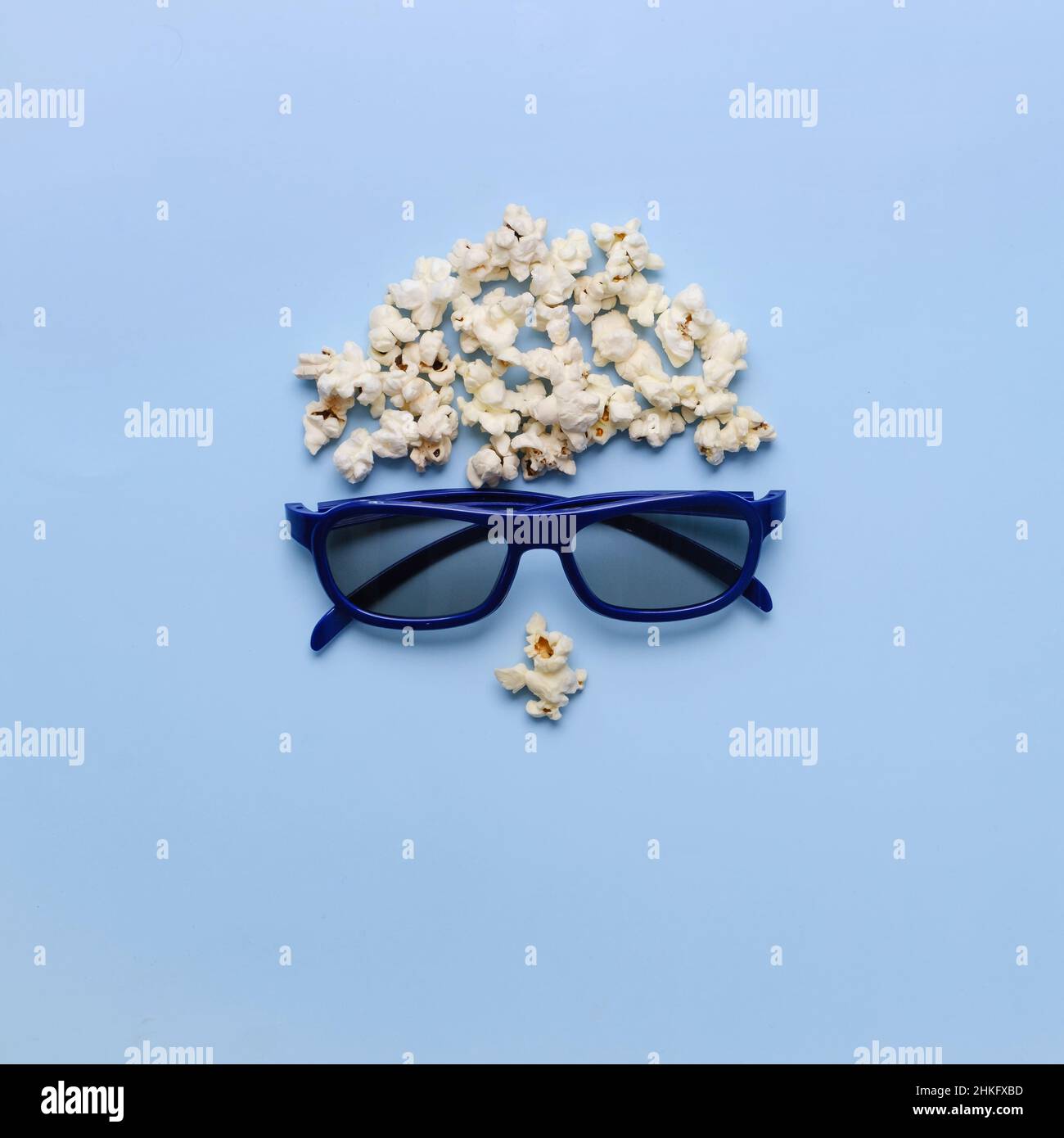 Pop Corn man Gesicht auf blauem Hintergrund. Kinokonzept. Draufsicht flach liegend mit Kopierplatz. 3D Brillen für romantische Filme für Paare. Stockfoto