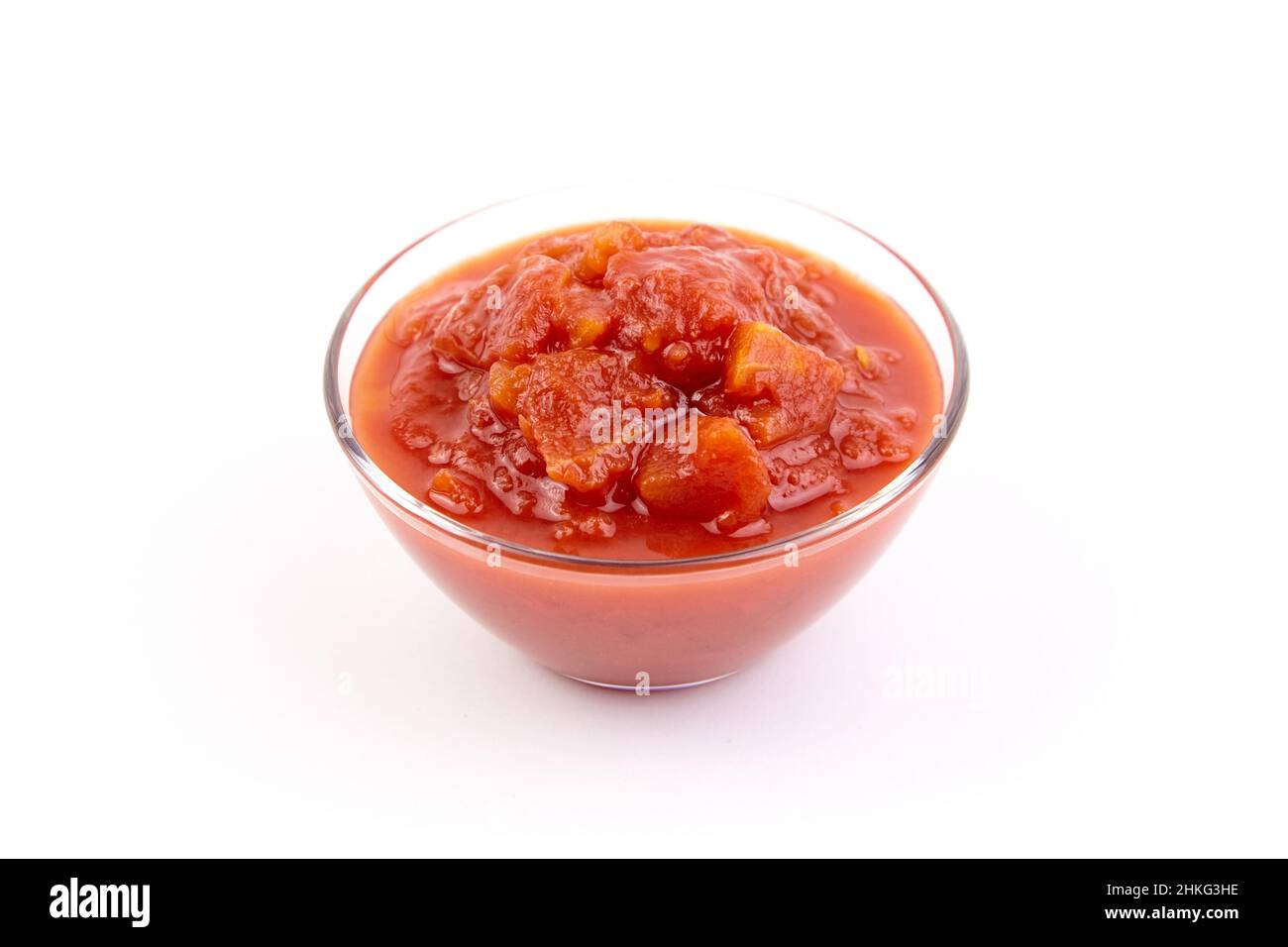 Gehackte Tomaten in Tomatensaft in Glasschüssel isoliert auf weißem Hintergrund Stockfoto