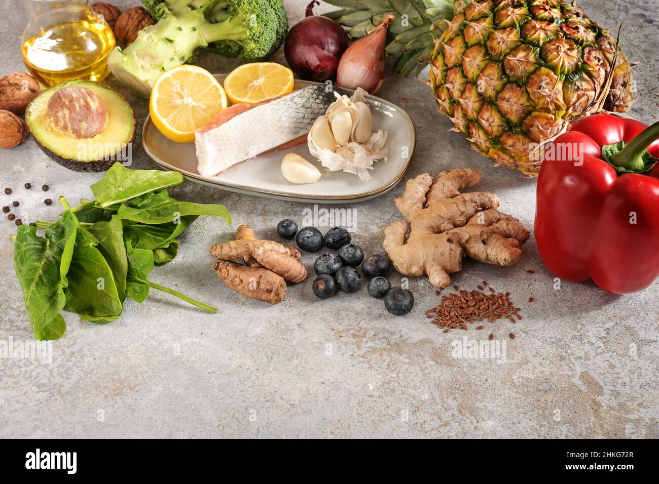 Set aus frischem Gemüse, Fisch, Früchten, Nüssen und Gewürzen für eine entzündungshemmende und antioxidative Ernährung, gesundes Lebensmittelkonzept, hellgrauer Steinrückstand Stockfoto