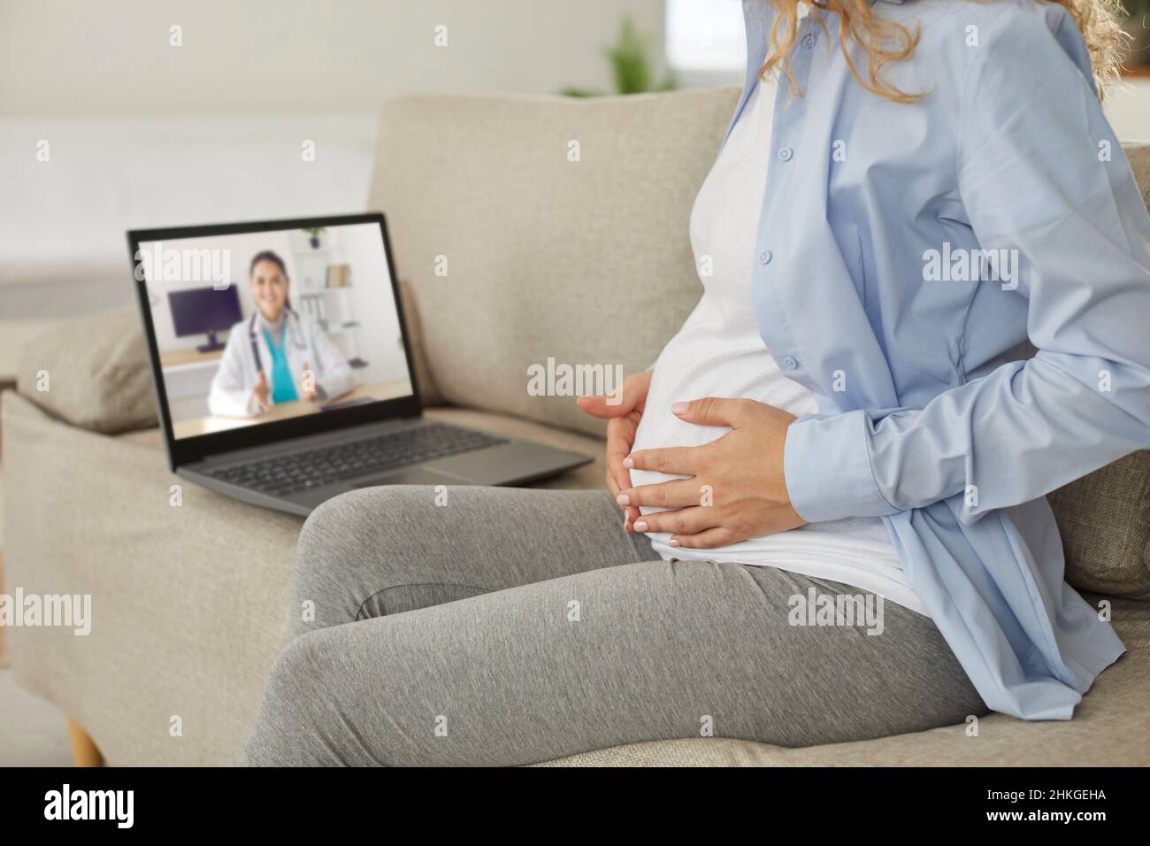 Junge Schwangerische Frau mit telemedizinischer Beratung mit Online-Arzt auf Laptop Stockfoto