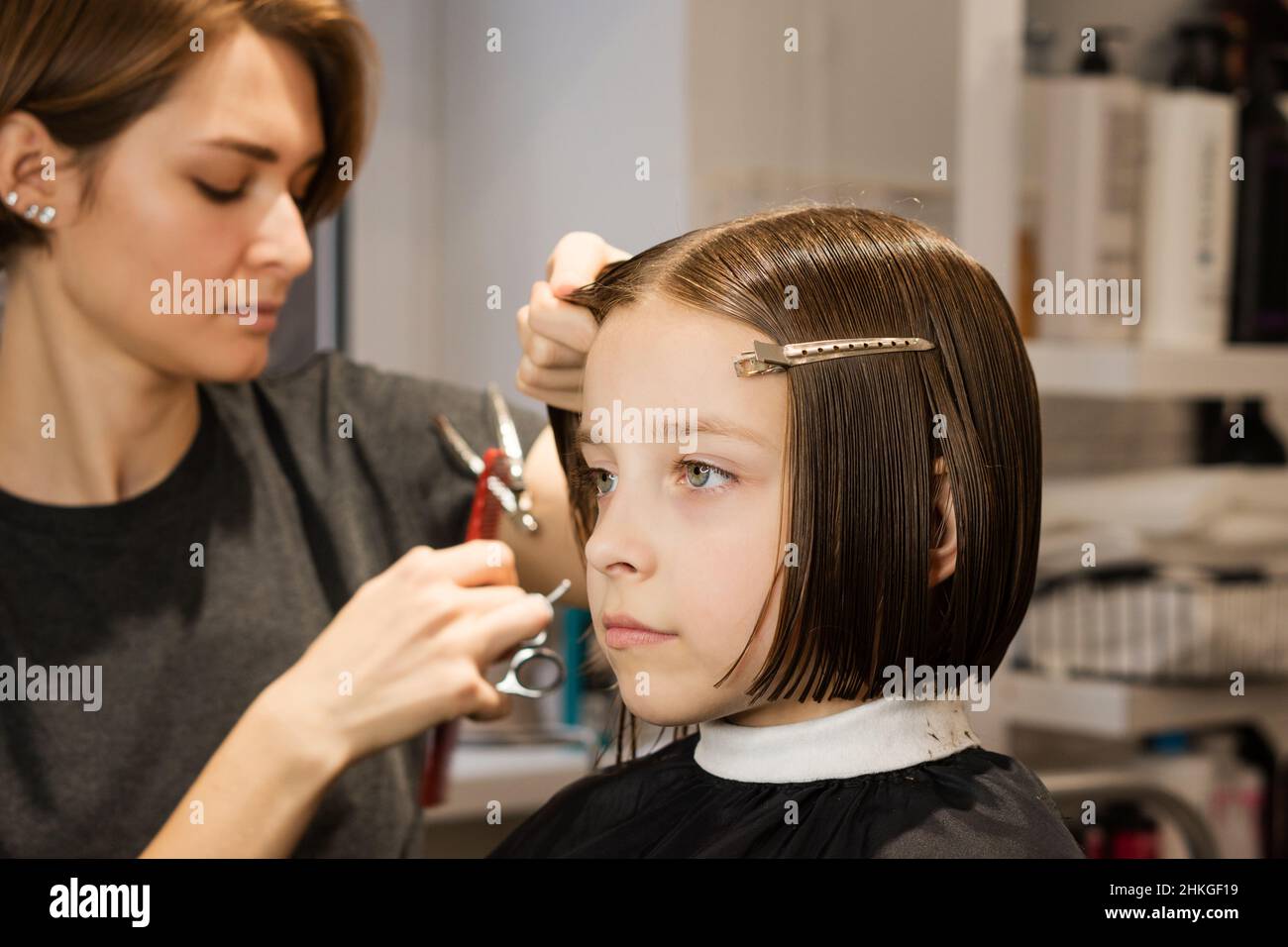 Schönheit Mode Kind Modell Bob Kurze Frisur. Kleines Mädchen Client mit kurzen Bob Haar. Friseursalon schneidet ihr die Haare. Prozess. Kurse in Friseursalon. Schönheitskonzept. Stockfoto