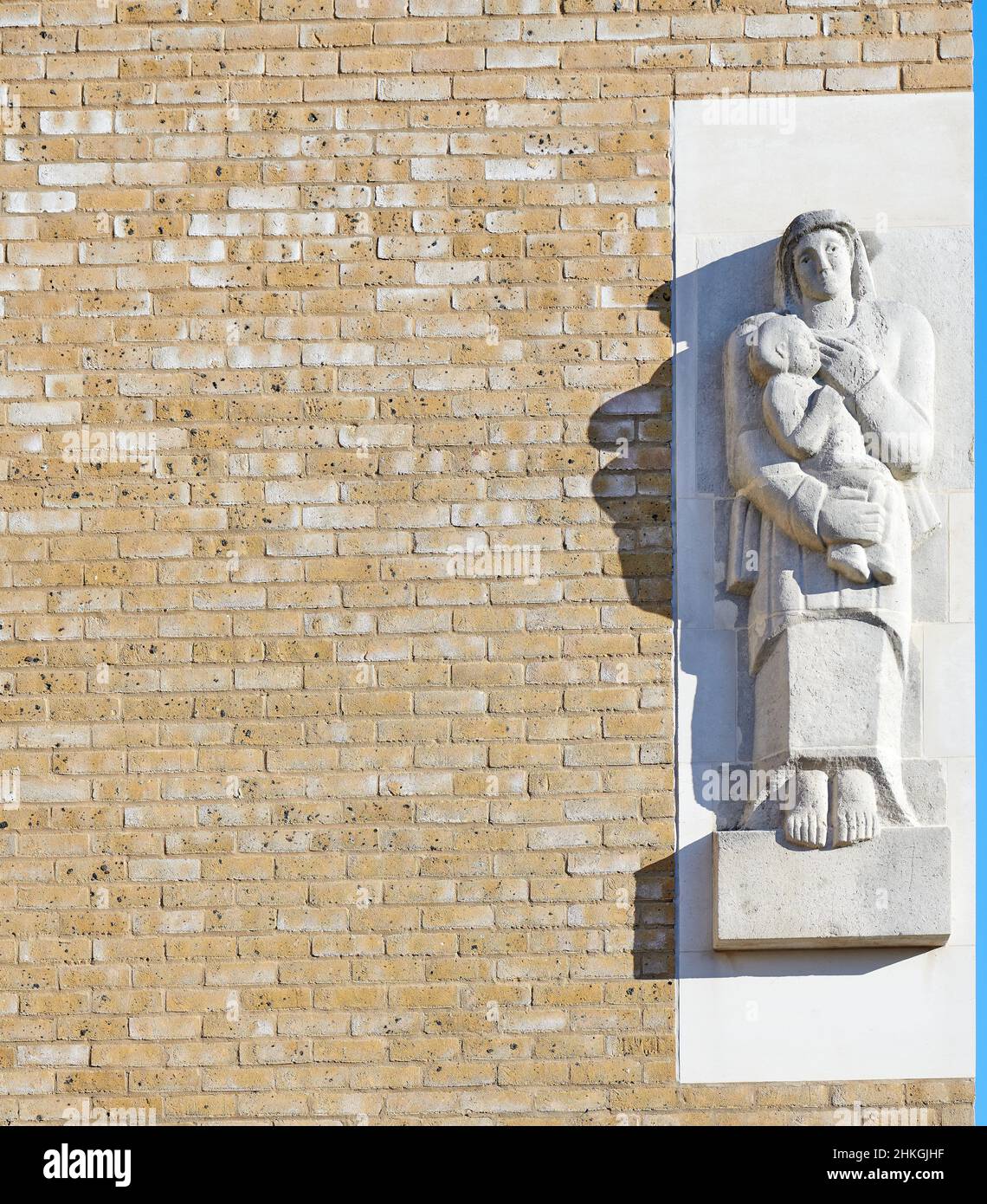 Mutter-Kind-Steinskulptur auf einer Ziegelmauer im Radcliffe Observatory Quarter, Universität Oxford, England. Stockfoto