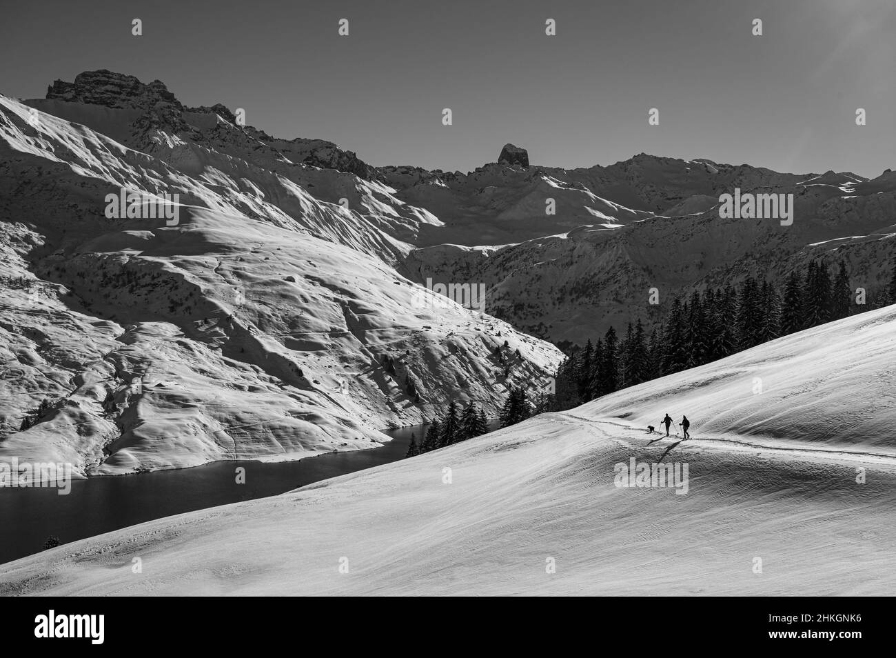 Schwarz-Weiß-Bild von zwei Menschen, die einen schneebedeckten Berg in Frankreich, Europa, wandern. Stockfoto