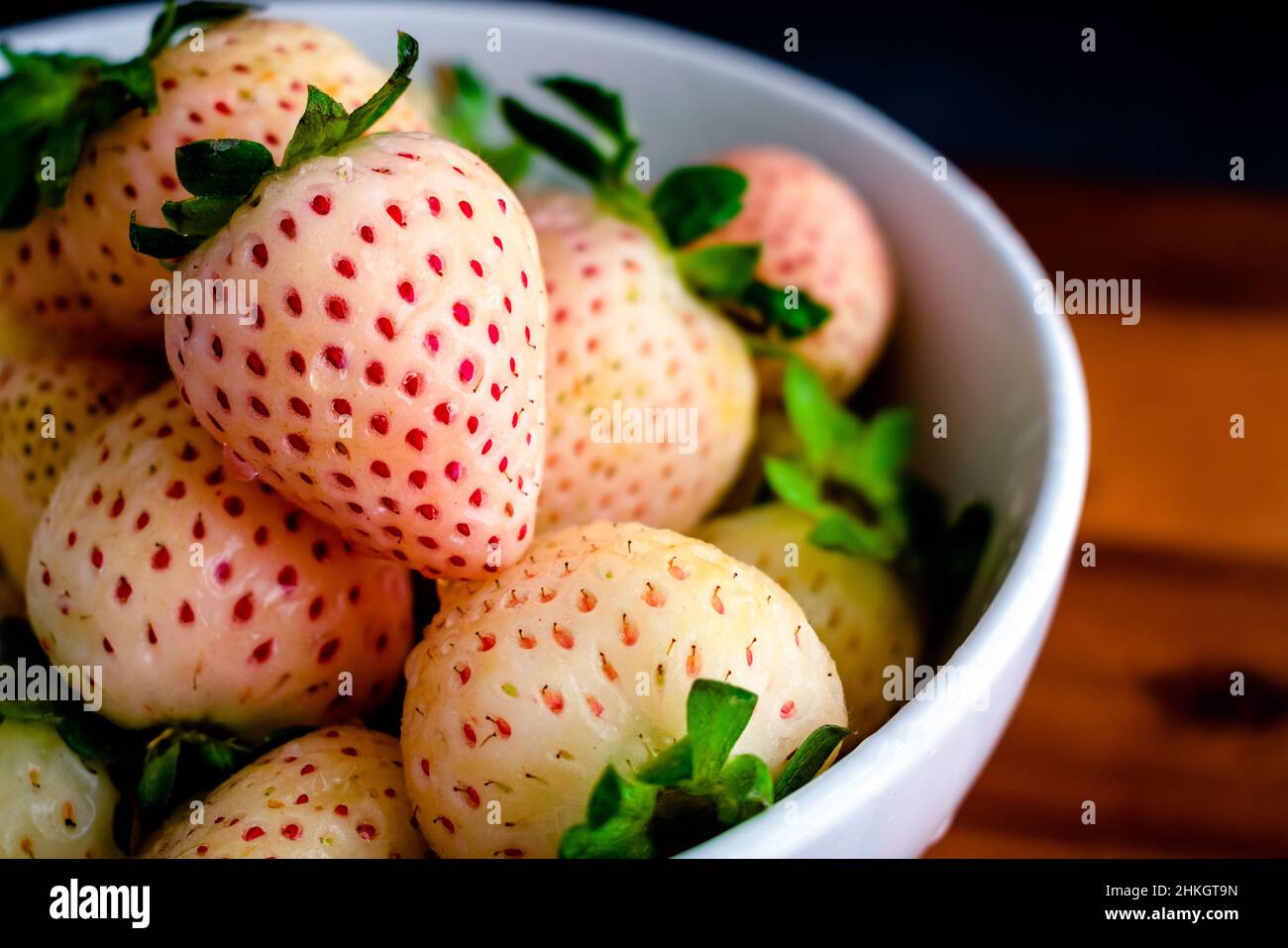 Frische weiße Weinbeeren mit Wassertropfen: Nahaufnahme von ganzen feuchten weißen Erdbeeren in einer Keramikschale Stockfoto