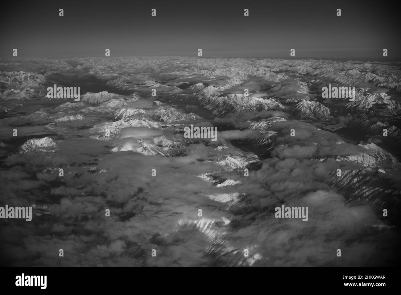 Blick auf schneebedeckte felsige Berge Kanadas zwischen Alberta und British Columbia vom Fensterplatz des Flugzeugs auf klaren Wintertagen Stockfoto