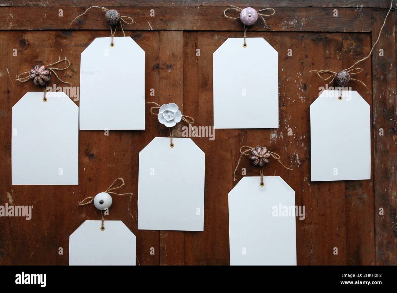 Leere Notizen auf rustikalem Holz, die an einer Vielzahl von Knöpfen hängen Stockfoto