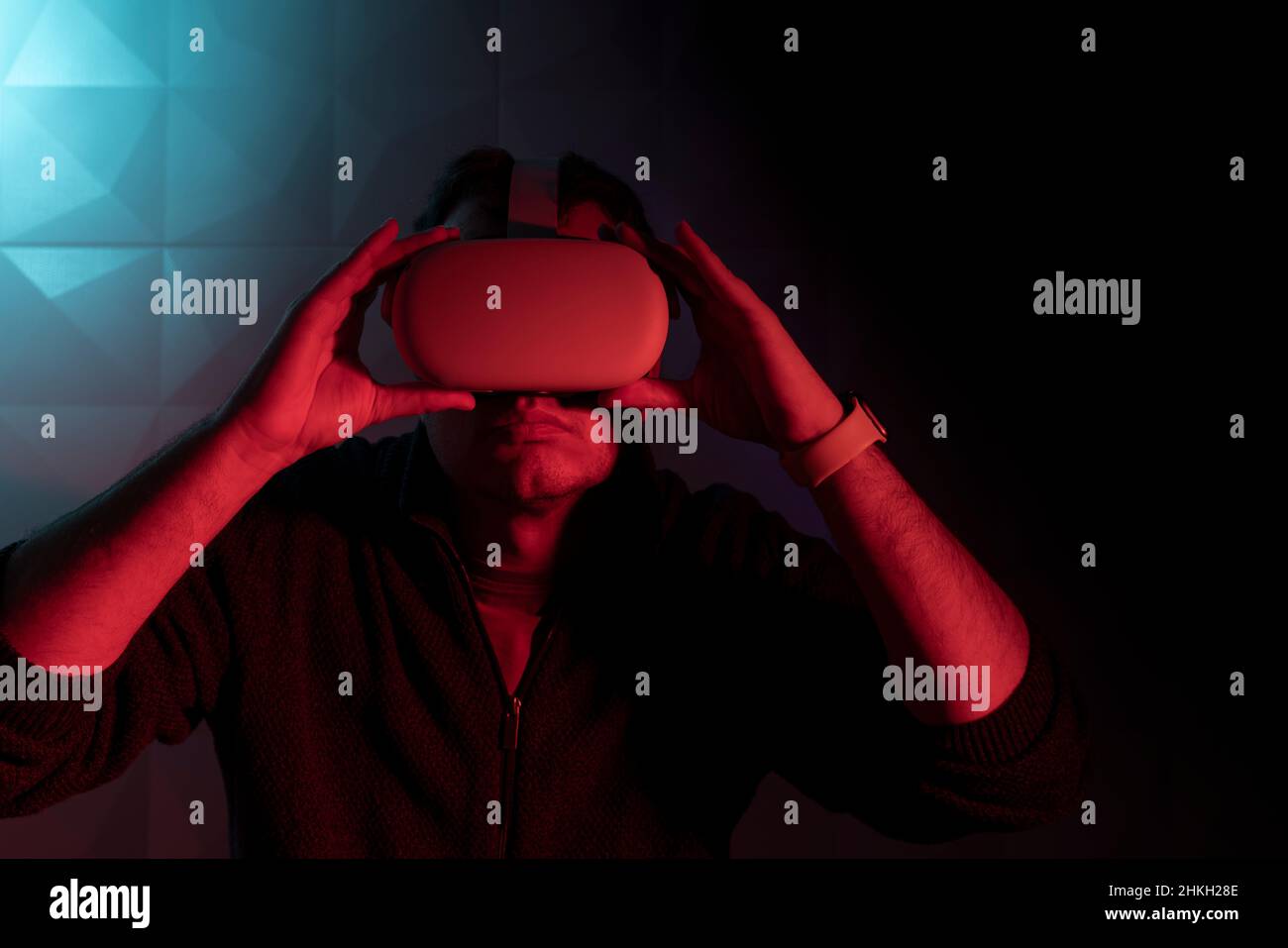 Mann mit weißer Virtual-Reality-Brille mit im roten Licht im Dunkeln Stockfoto