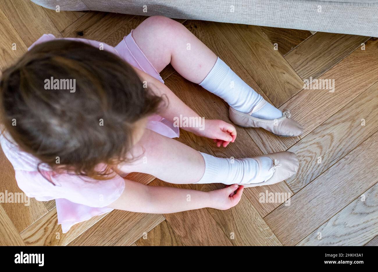 Freche junge 5-jährige Mädchen setzen auf ihre Ballettschuhe bereit für einen Tanzkurs Großbritannien Stockfoto