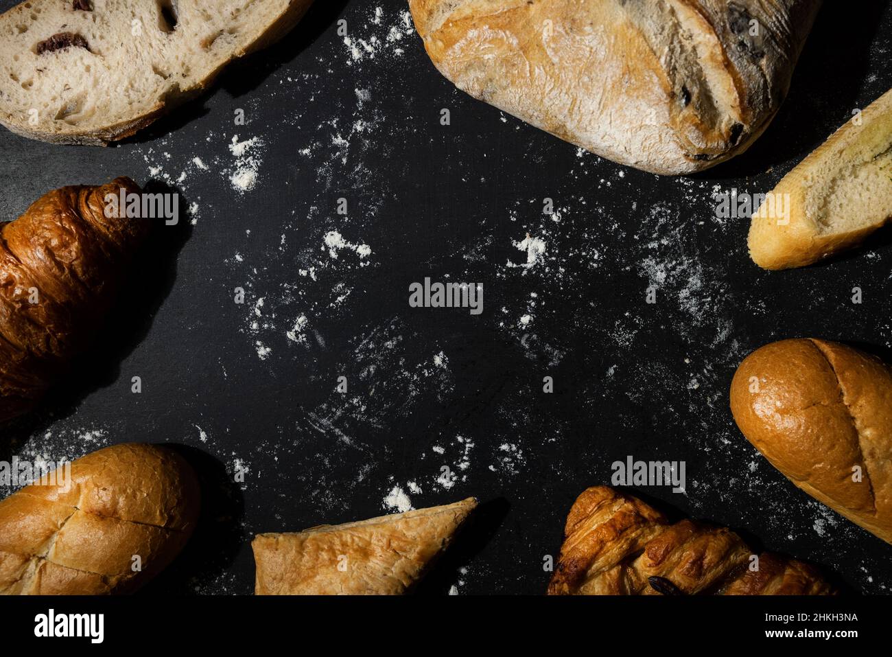 Bäckerei - Brot und Gebäck mit Mehl auf schwarzem Hintergrund. Copy space Stockfoto