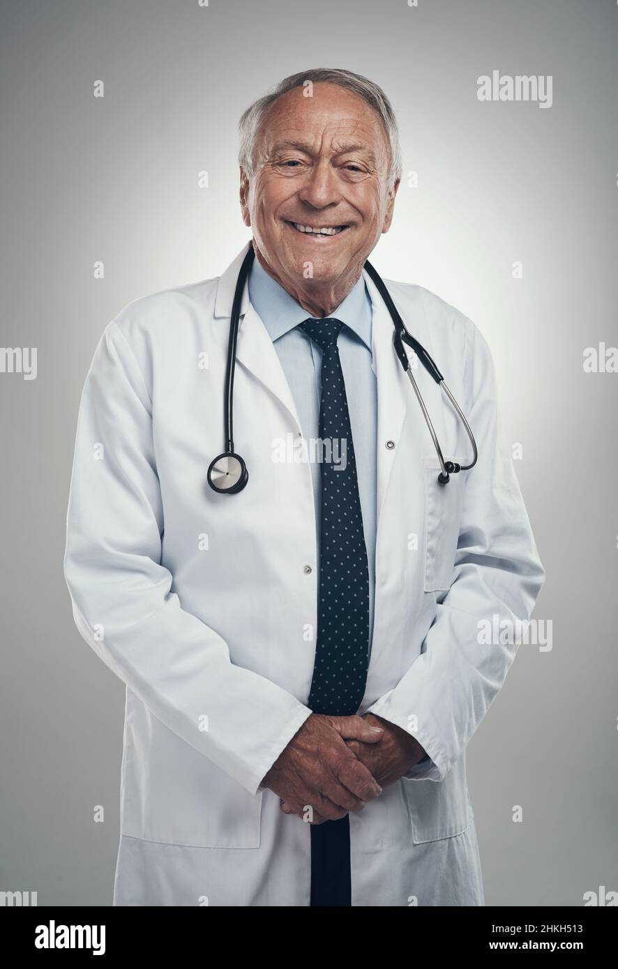 Nicht alle Helden tragen Umhänge. Aufnahme eines älteren männlichen Arztes in einem Studio vor grauem Hintergrund. Stockfoto