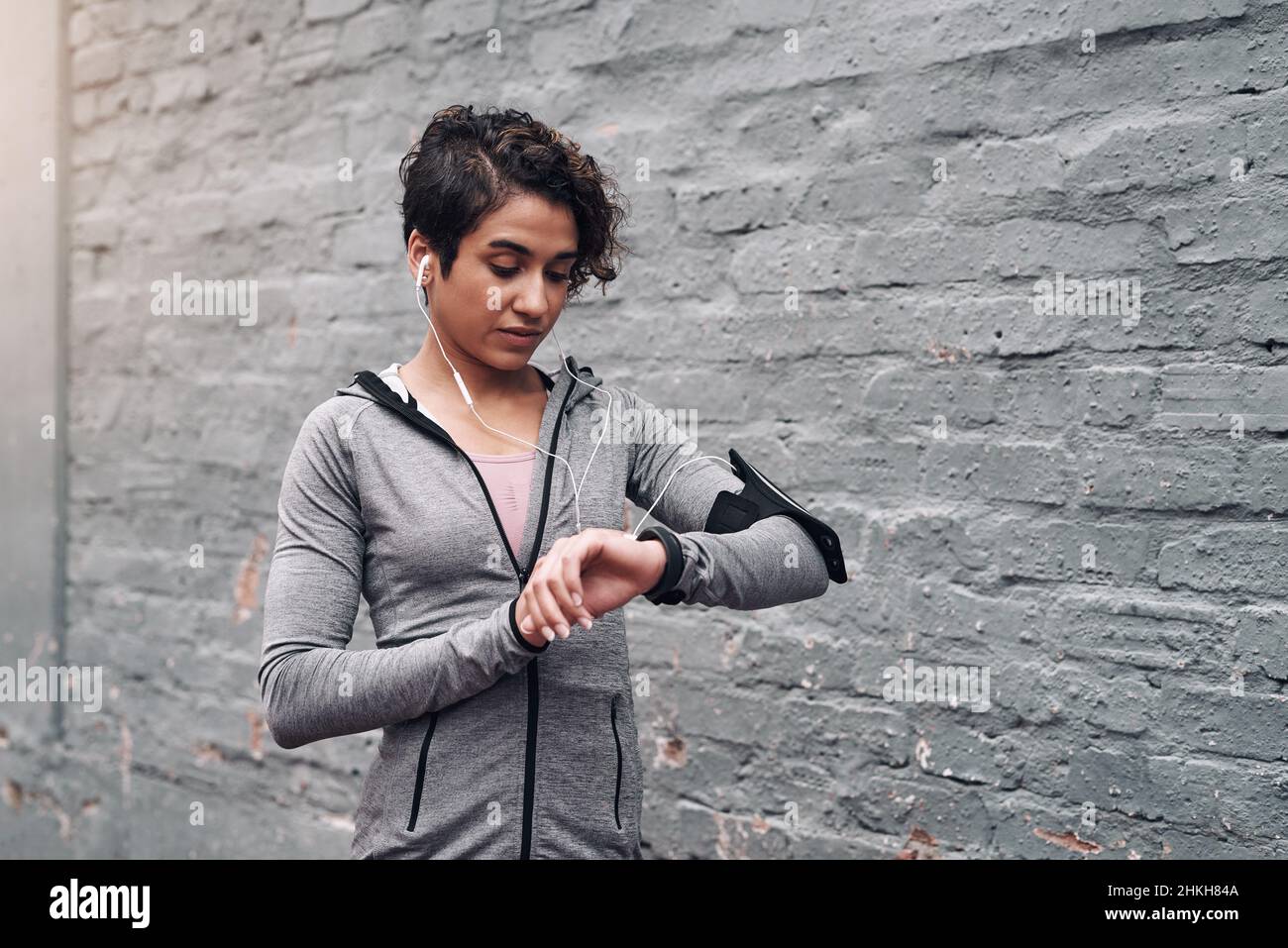 Geist über Materie. Aufnahme einer jungen Frau, die ihren Fitness-Tracker während eines Laufs draußen überprüft. Stockfoto