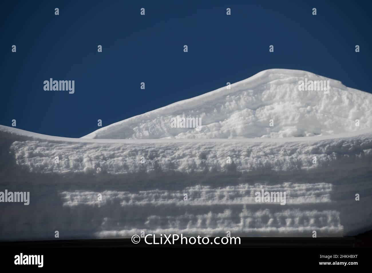 Schneeschichten auf dem Dach Schneelast auf dem äußeren Hausdach oder Ski-Chalet Ansammlung von Schnee im Winter blauen Himmel im Winter Hintergrund horizontalen Format Stockfoto