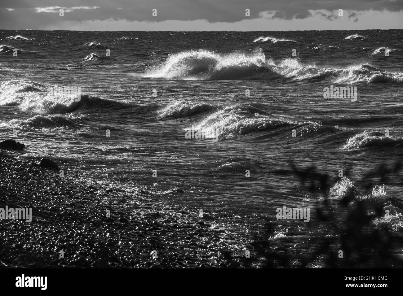 Schwarz-Weiß-Bilder von Wellen, die am Herbsttag am Strand des Süsswassersees Ontario in Ontario, Kanada, aufprallen, und Wolken im Hintergrund Stockfoto