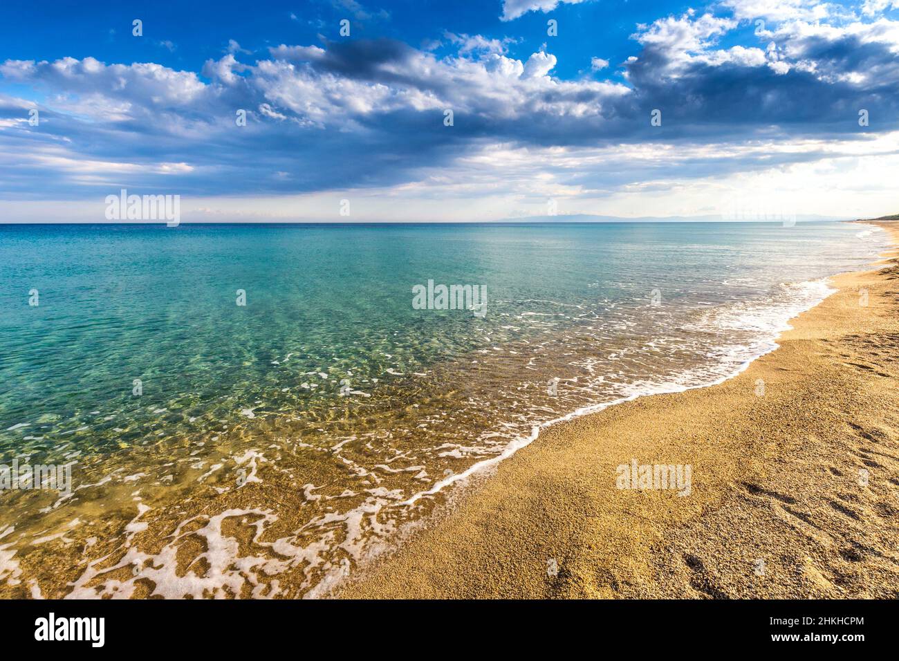Sandstrand am Ufer des ruhigen türkisfarbenen Meeres und Wolken am blauen Himmel in Italien, Europa. Stockfoto