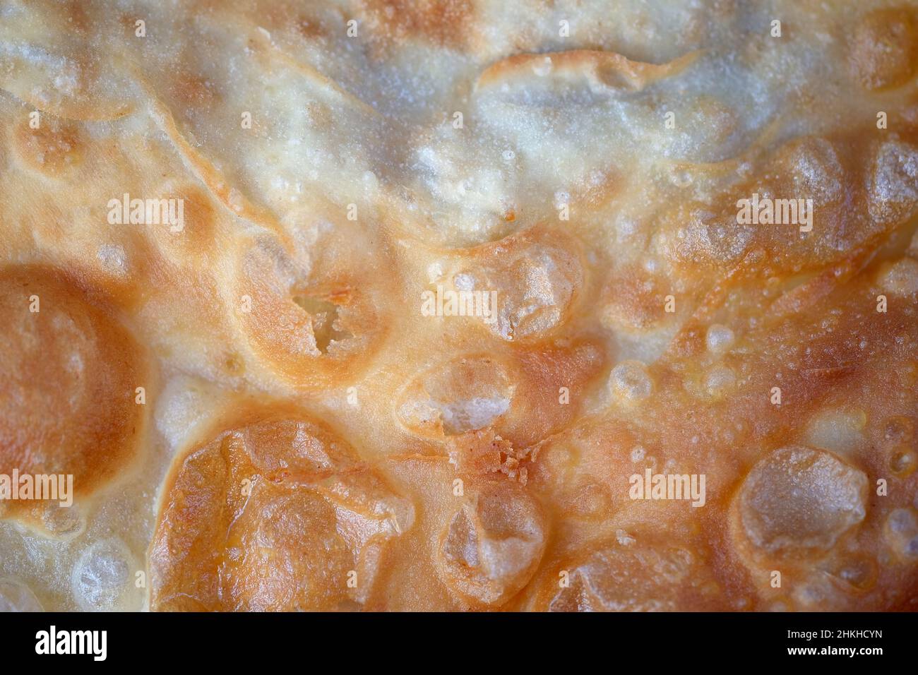 Chebuk Nahaufnahme Hintergrund. Frittierten dünnen Teig in Öl mit Blasen. Chebuk Textur Draufsicht. Textur von gebratenen Teignahrung. Stockfoto